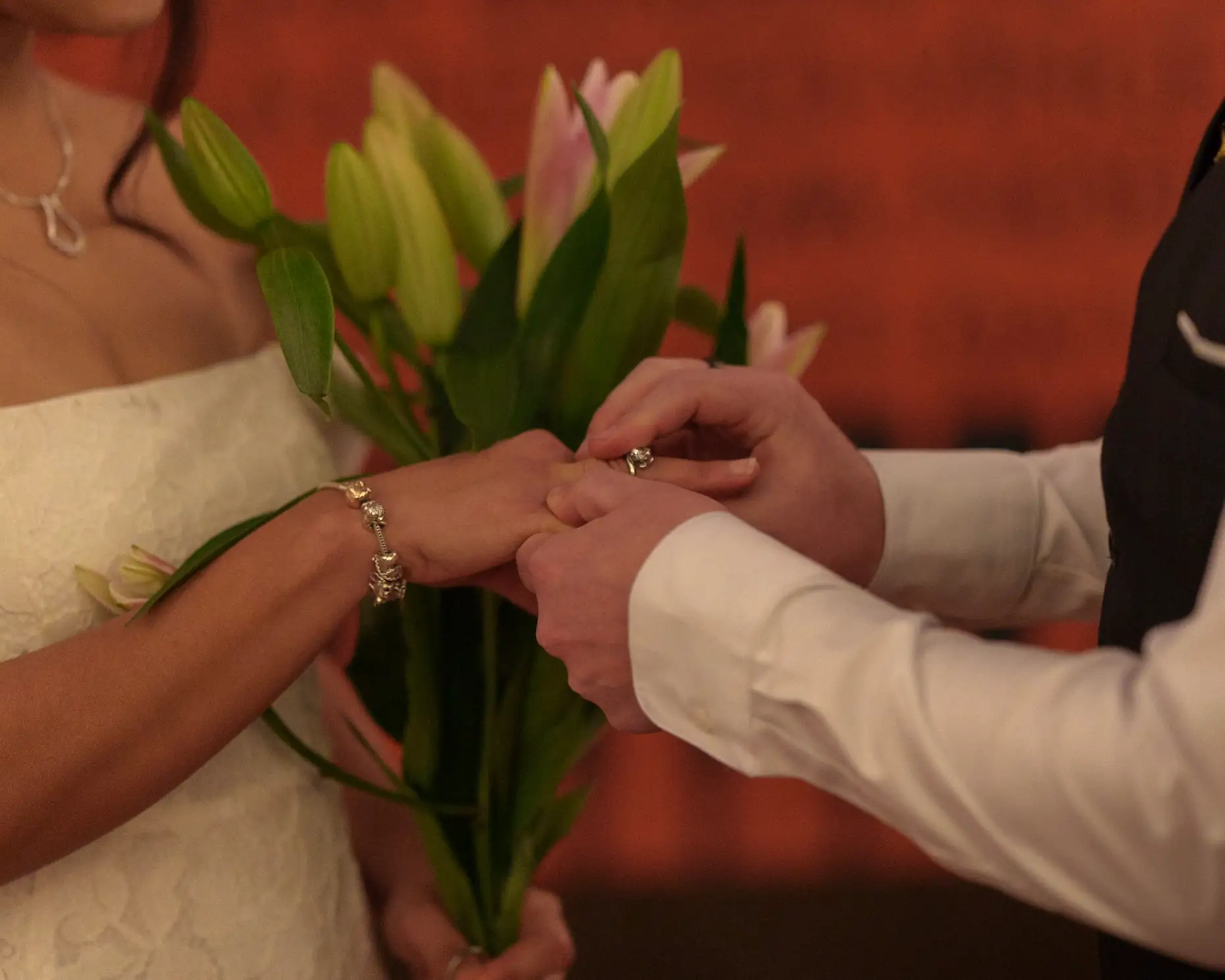A detail of a bride and groom holding a boquet together