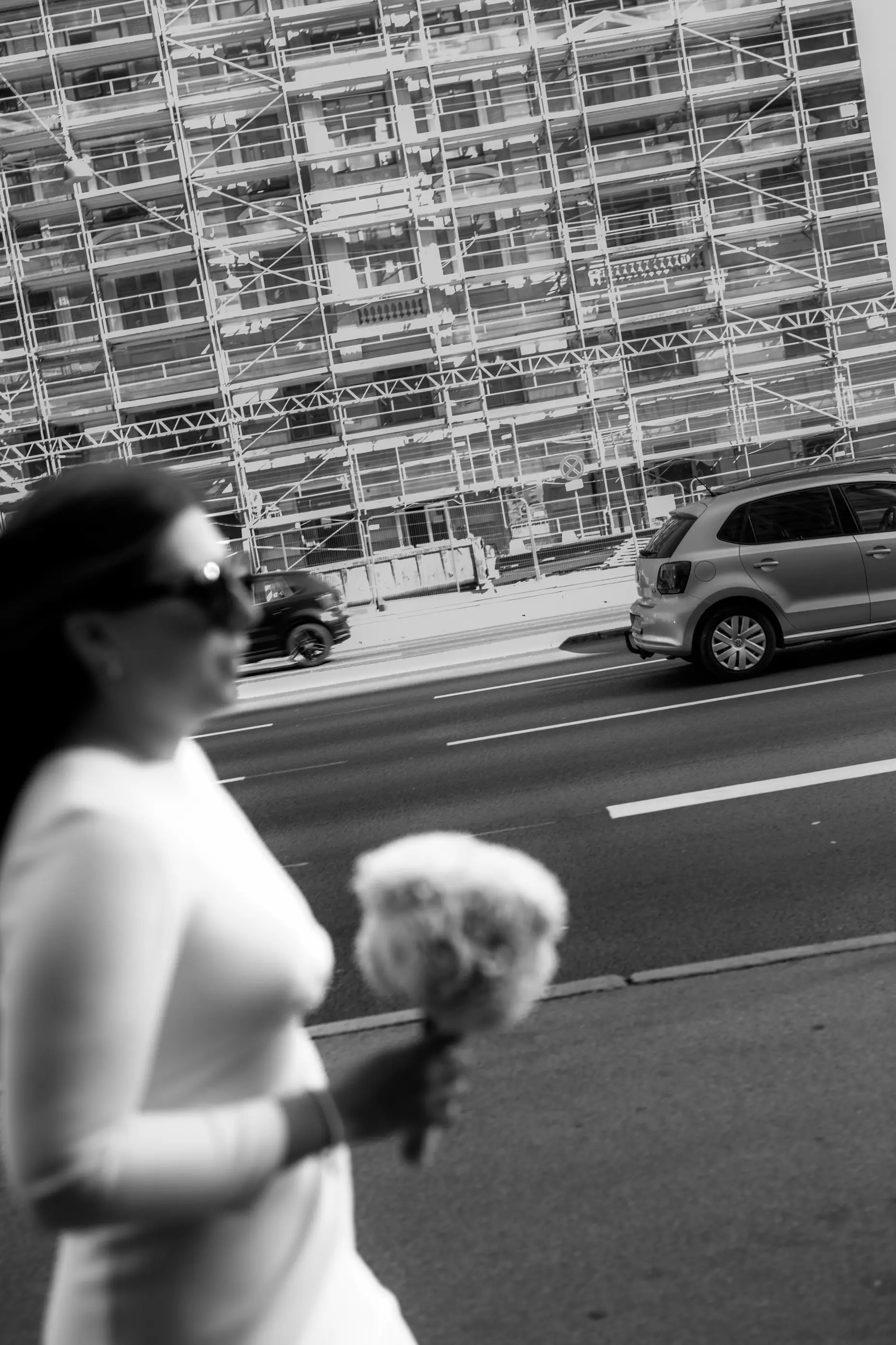 Bride walking down a street with a boquet in her hands.