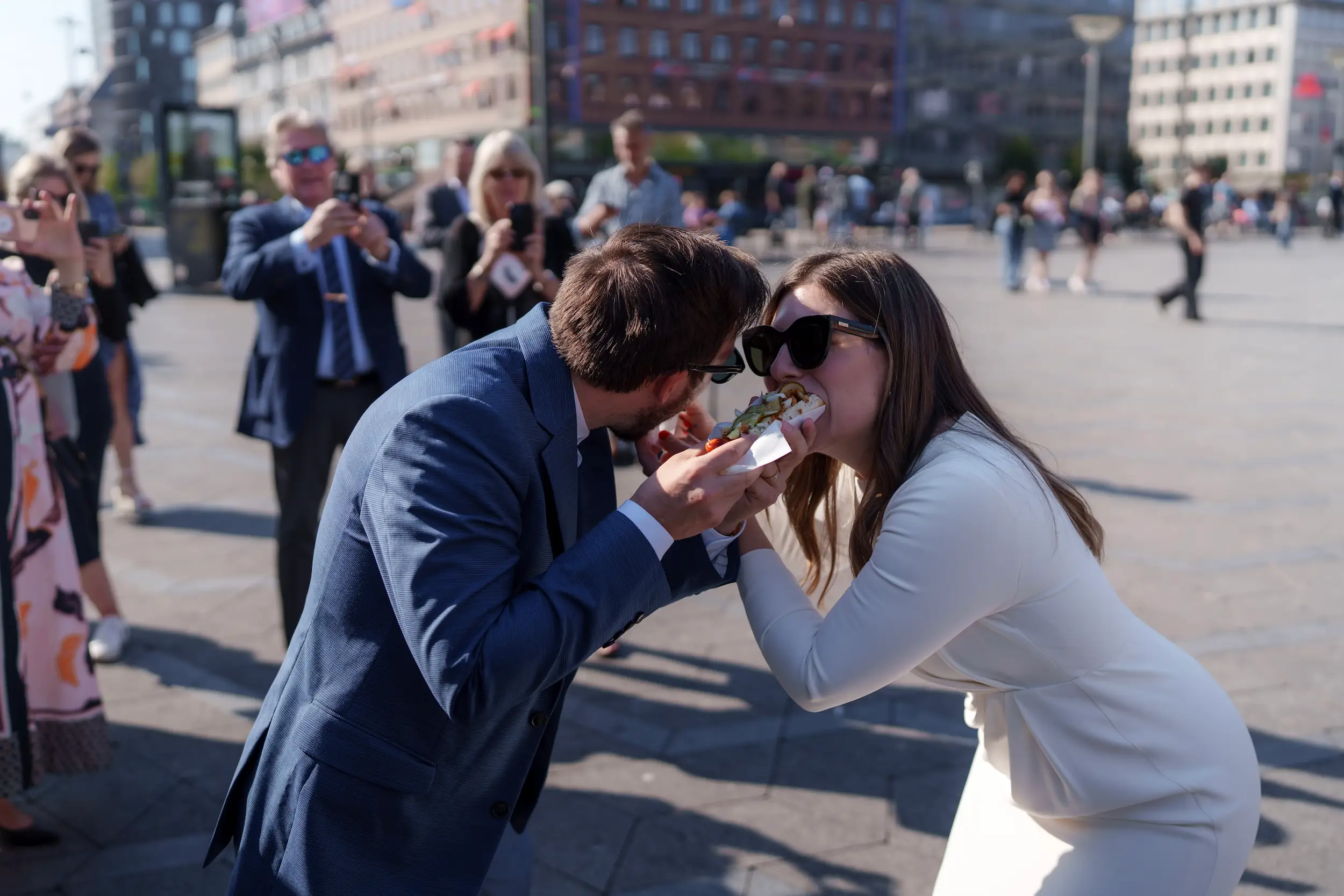 Bride and groom share a bit of a hot dog
