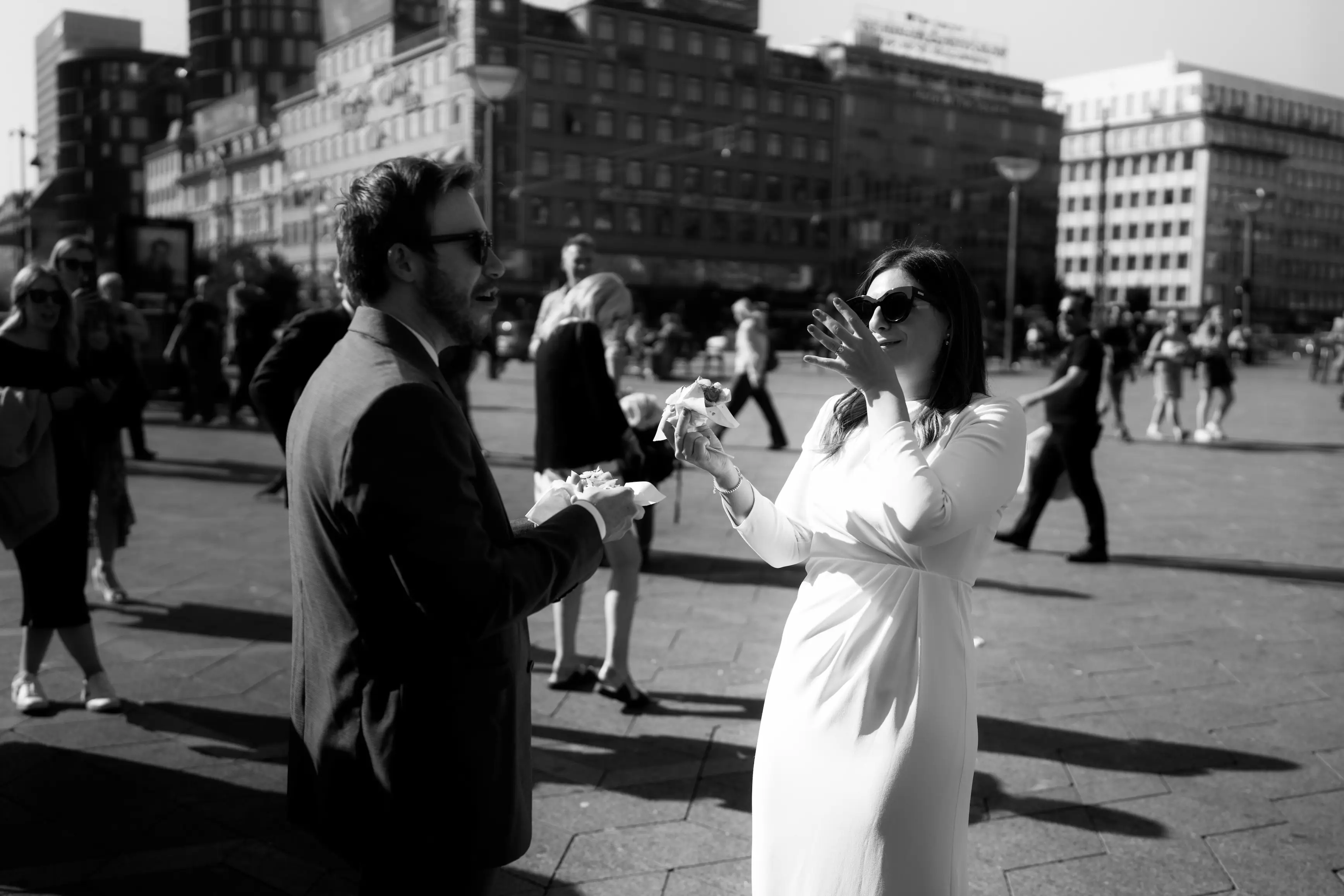 Bride and groom enjoying a meal in a busy street, black and white