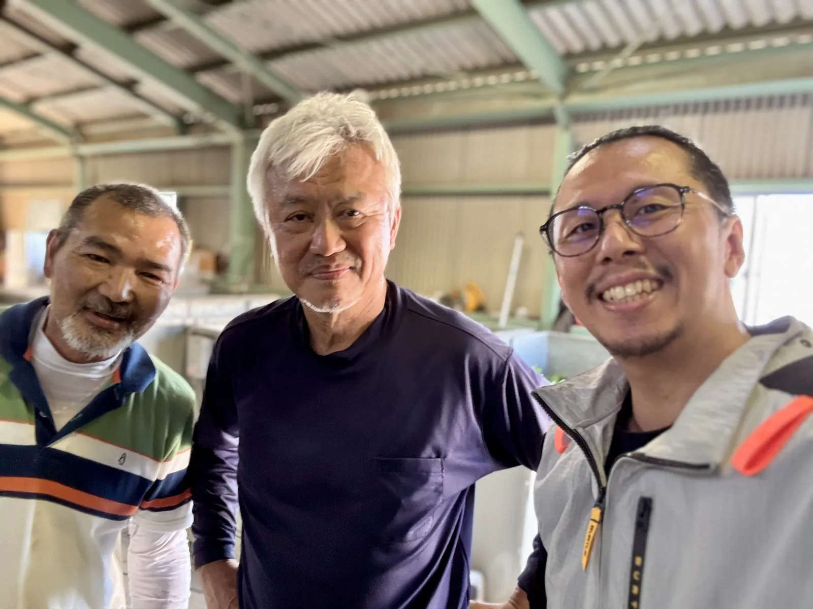 Three men standing together inside a Japanese tea processing factory.