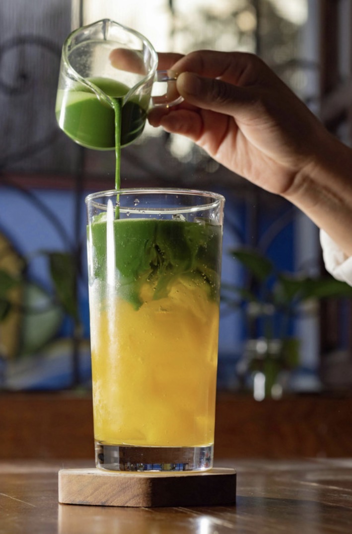 Matcha poured over a tall iced drink with citrus.