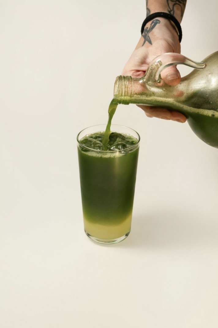 Matcha concentrate poured from a bottle into an iced glass.