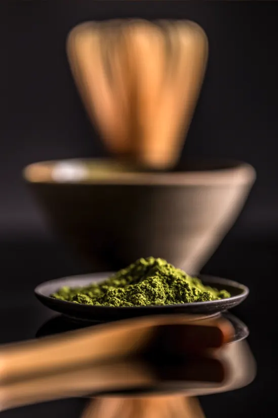 Dark matcha powder lit dramatically in a bowl