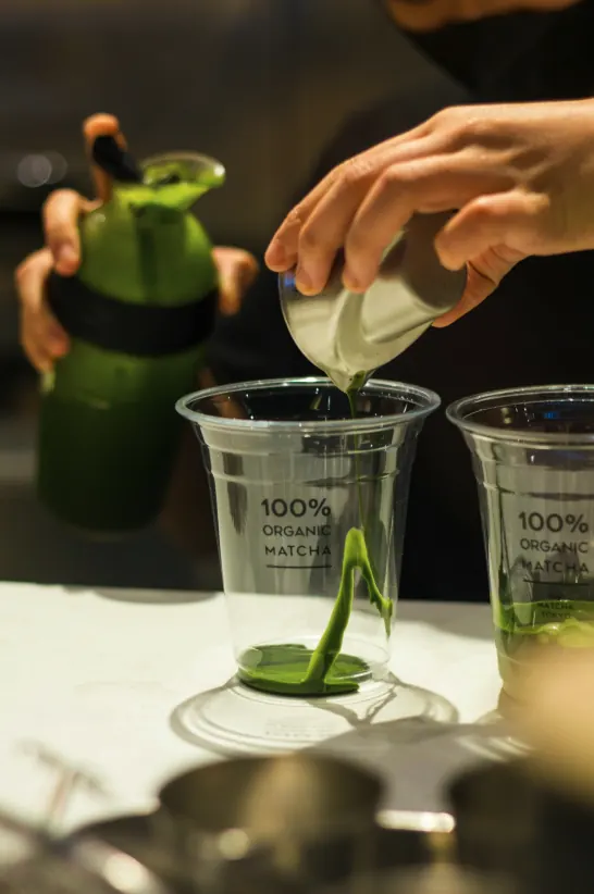 Matcha being poured into two glasses for cafe service