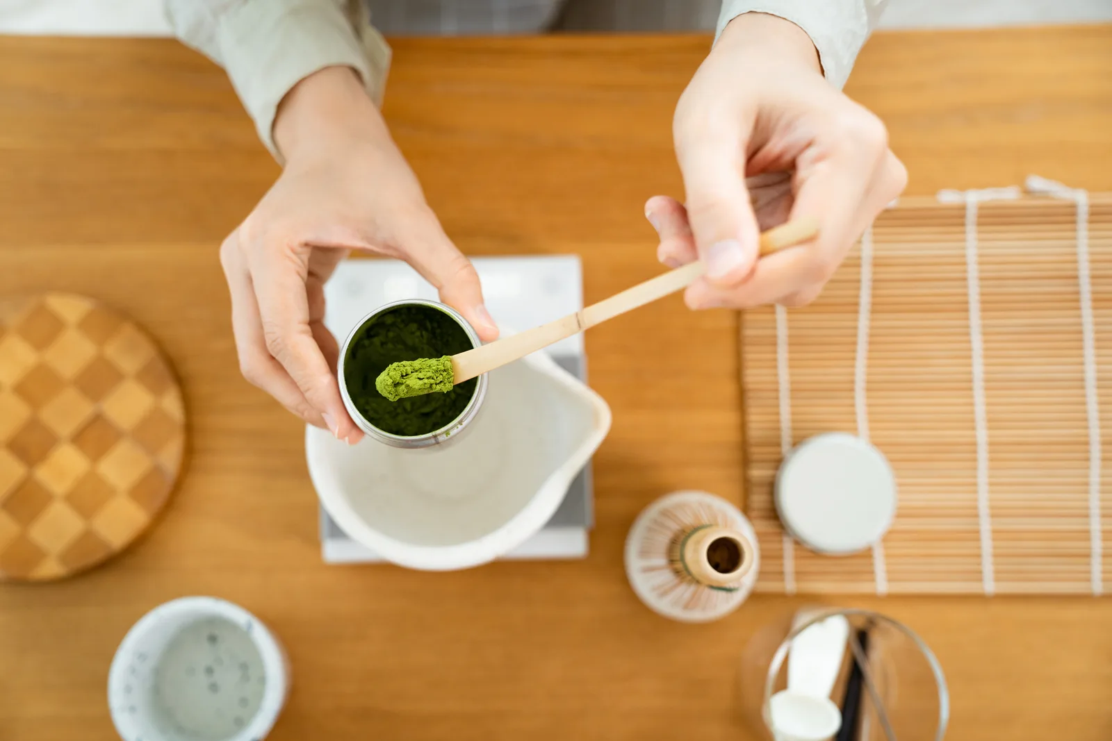 Matcha powder being scooped with a bamboo scoop, seen from above.