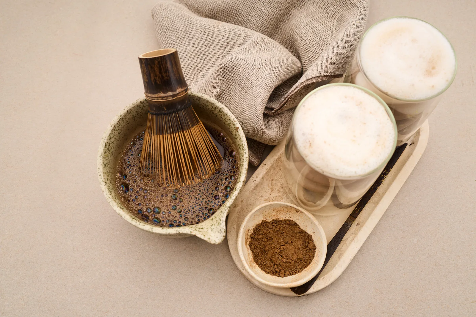 Hojicha powder being whisked with a bamboo whisk before milk is added.