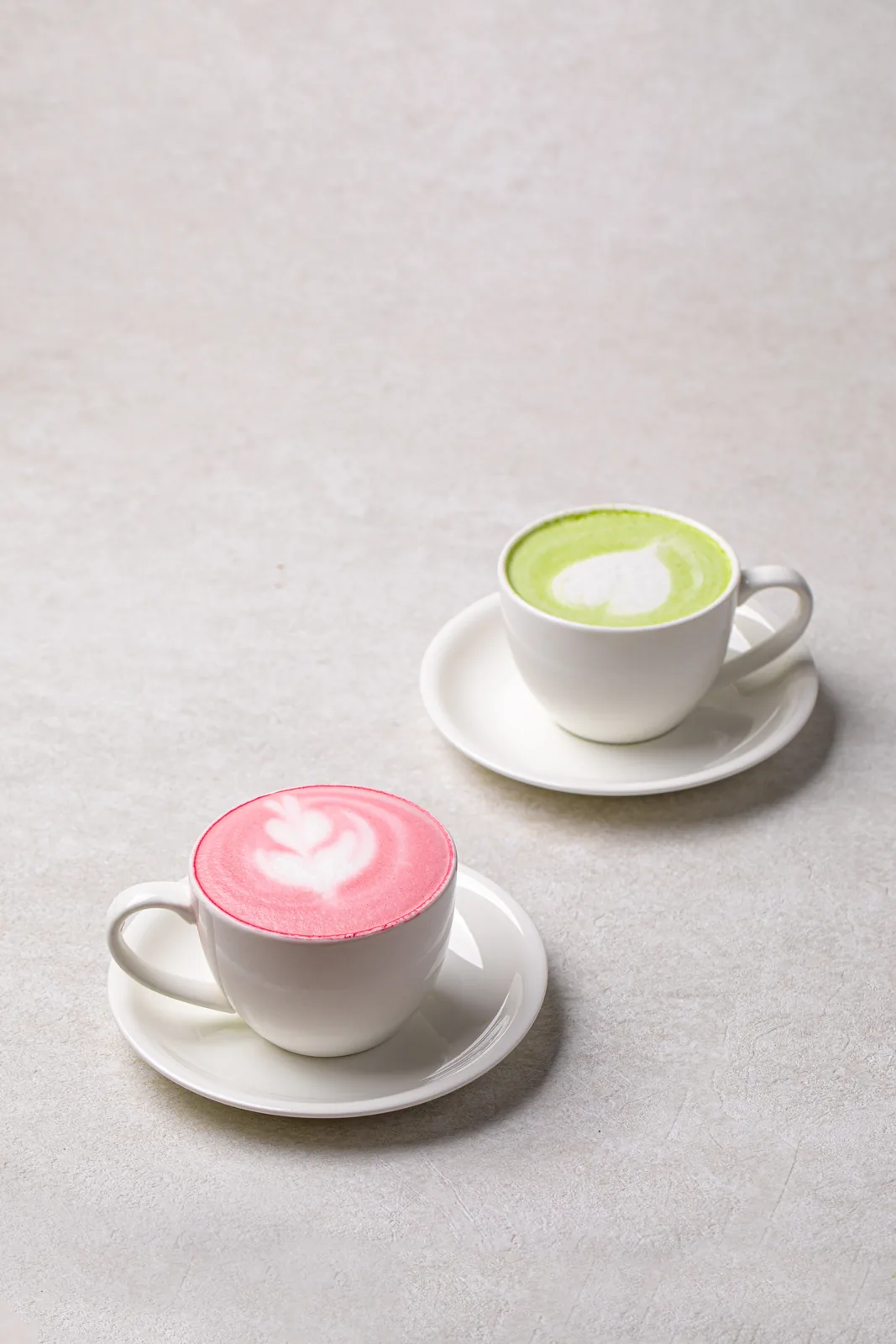 Two cups of different matcha latte drinks side by side.