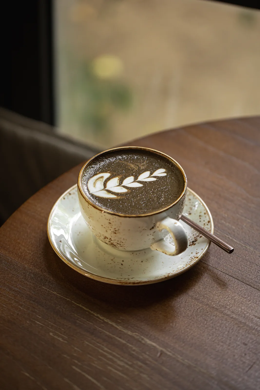 A hojicha latte with latte art on a cafe table.