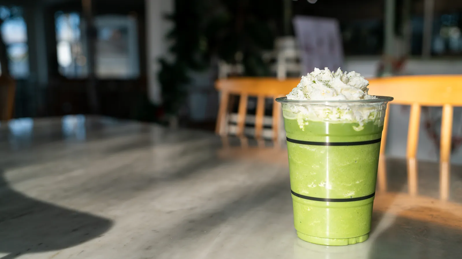 An iced matcha drink in a cup topped with a thick layer of cold foam.
