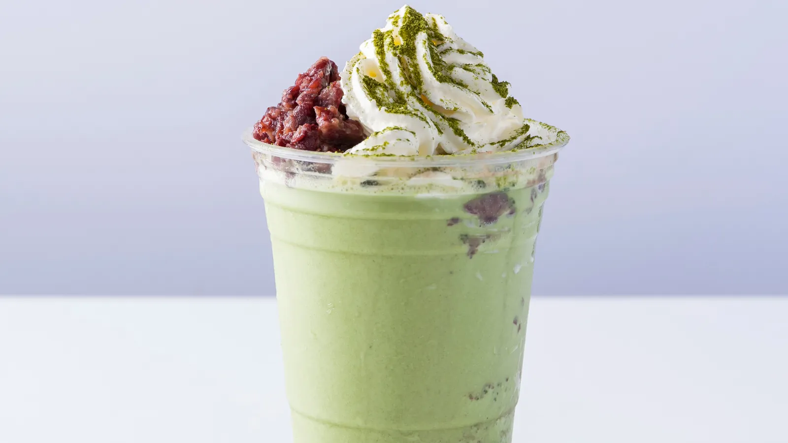 A blended matcha frappe topped with whipped cream and red beans, for the frozen matcha guide