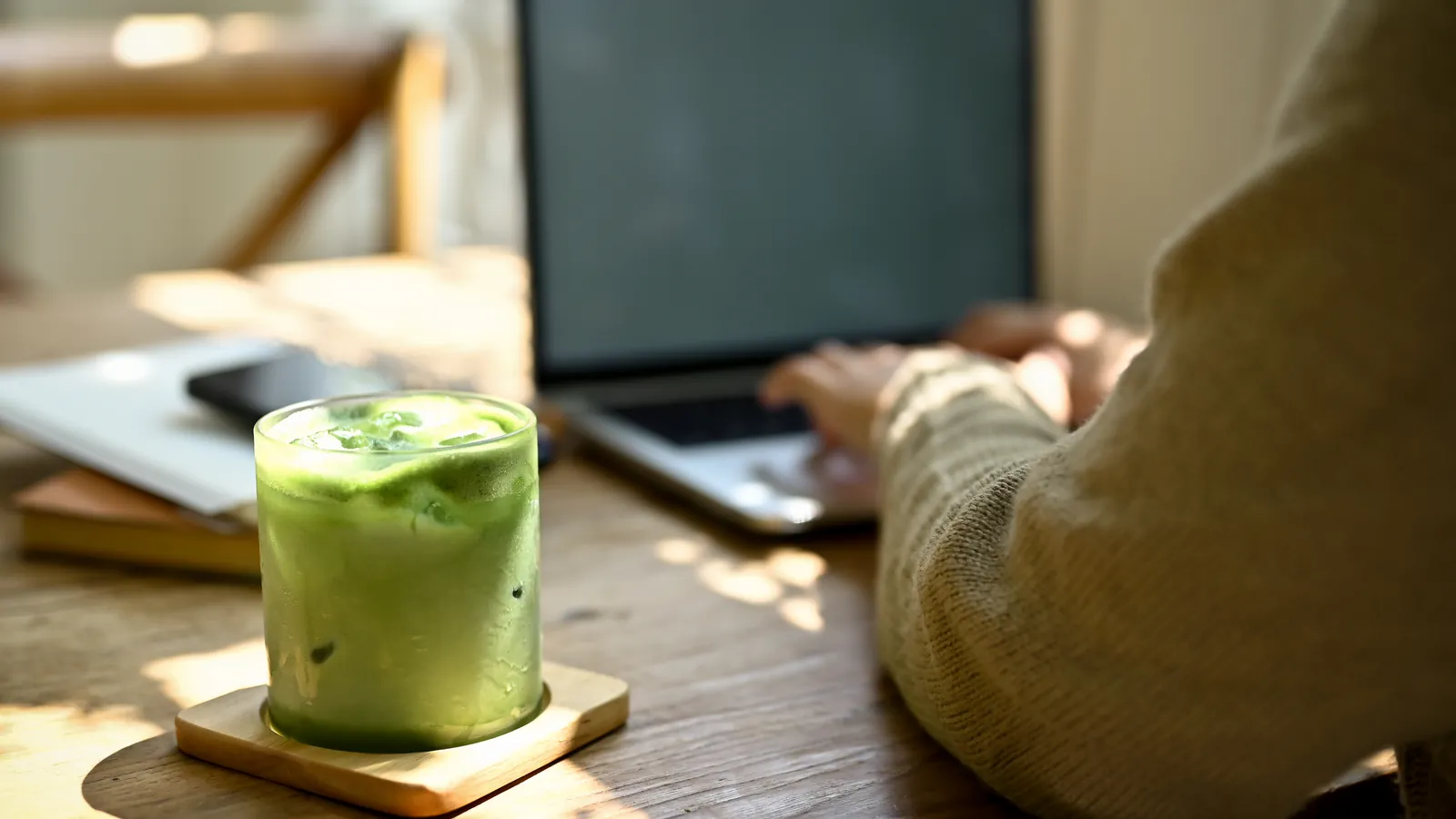 A glass of iced matcha on a wooden cafe table in the afternoon