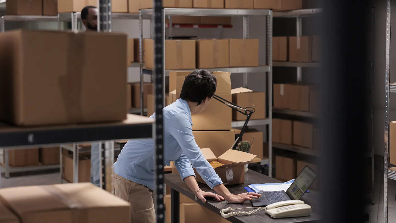 A worker checking shipping details against boxes in a warehouse