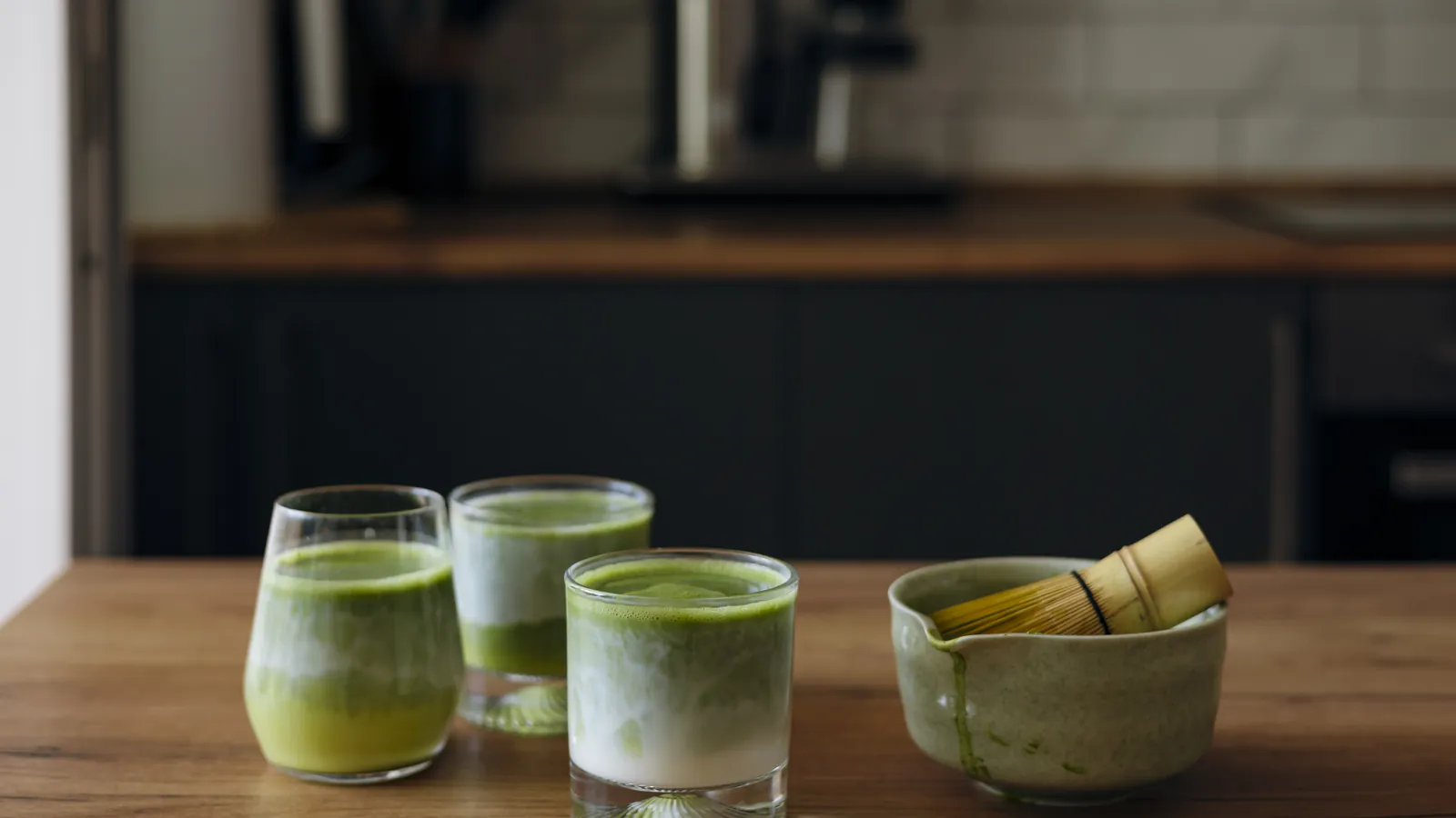 Glasses of matcha prepared with a bamboo whisk and bowl