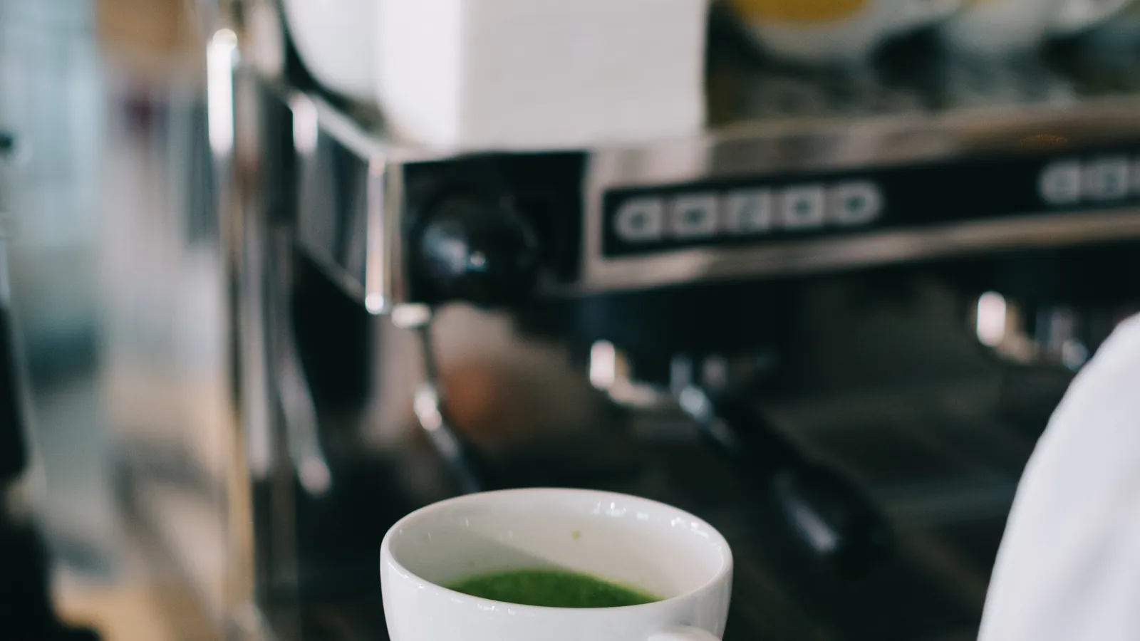 A barista preparing a matcha drink behind the bar