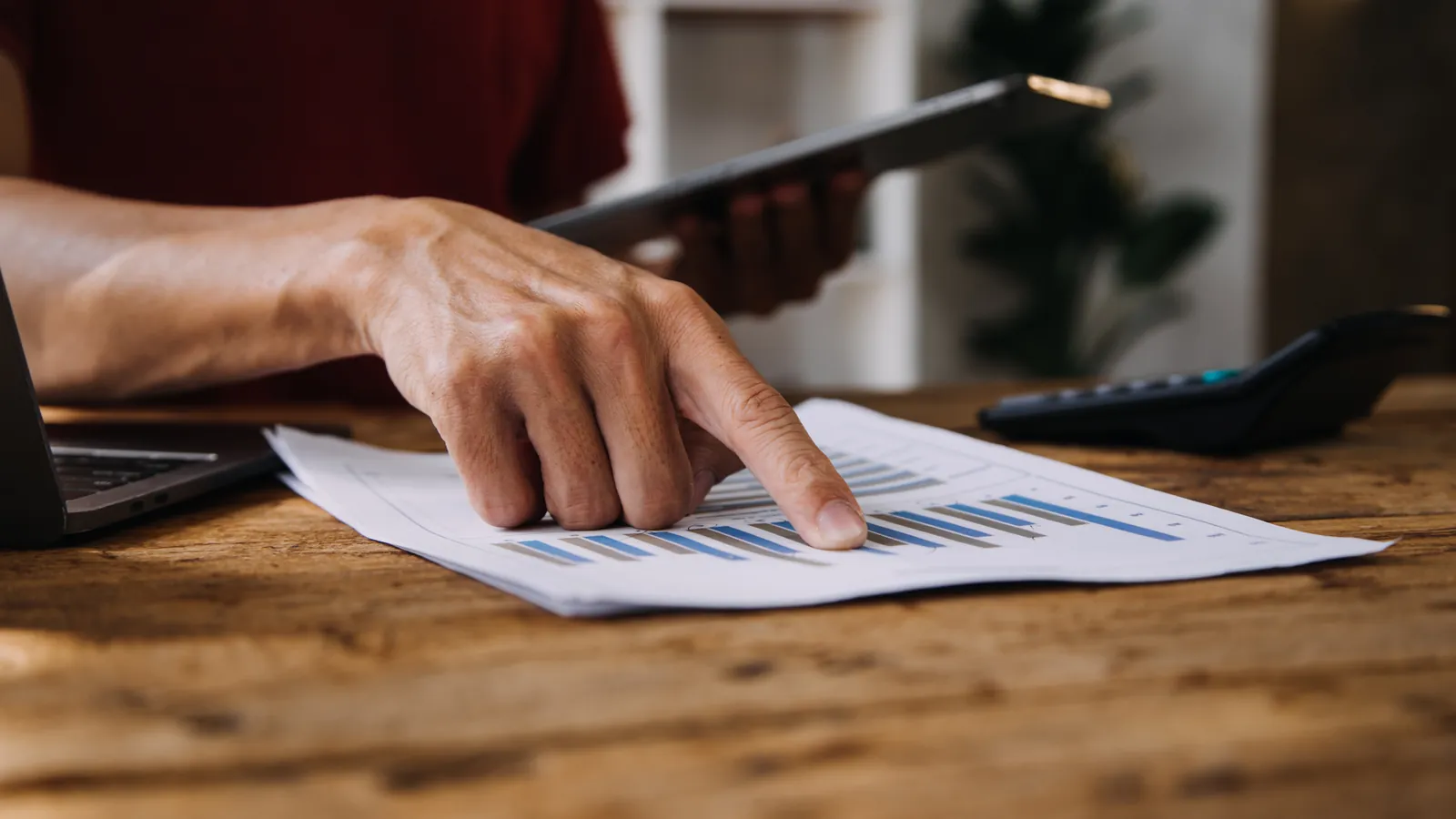 A hand working through printed figures on a desk