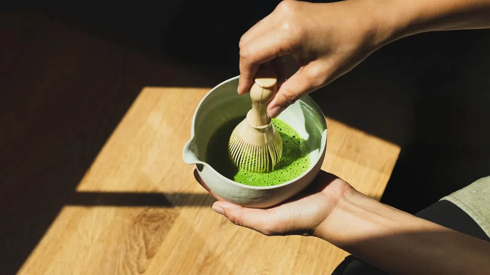 A bowl of matcha being whisked in daylight