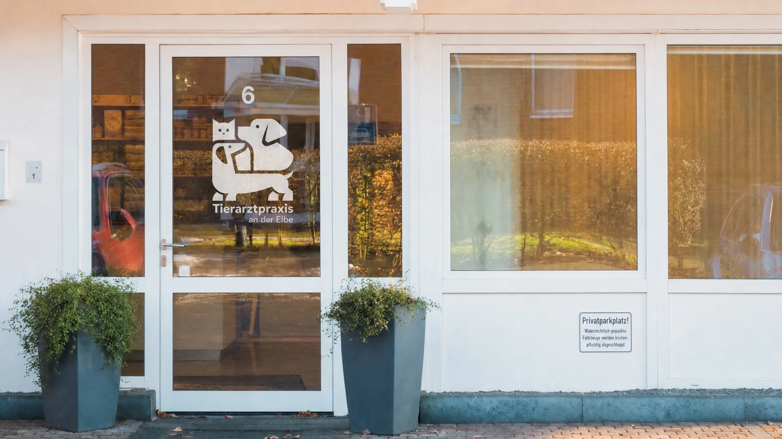 Eingang der Tierarztpraxis an der Elbe mit Logo und Parkplätzen direkt vor der Tür
