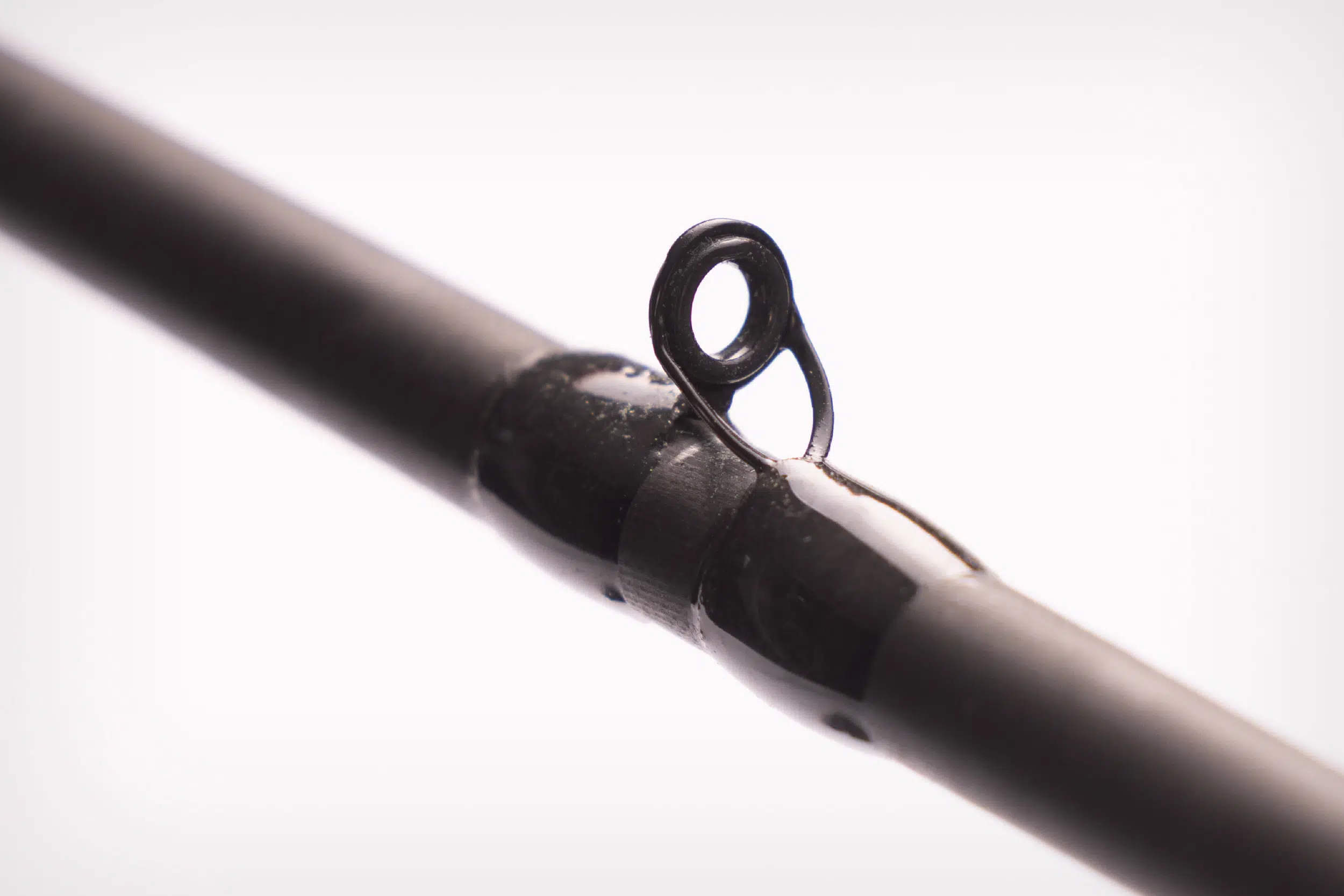 Close-up of a black fishing rod guide ring on a white background.