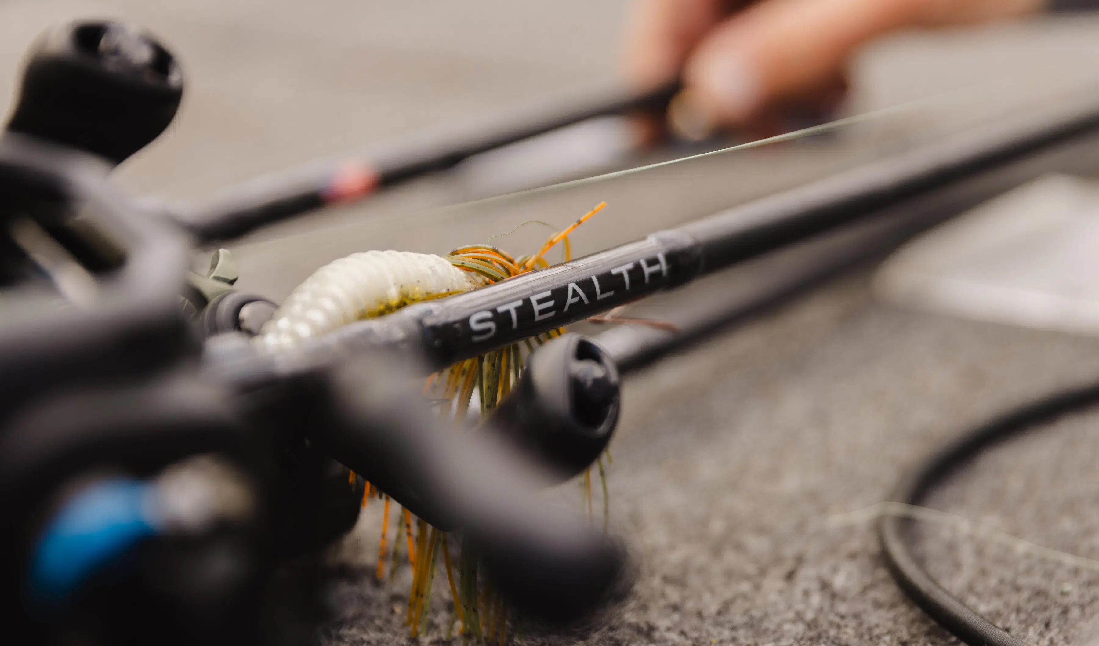 Close-up of a bow labeled STEALTH with a fishing lure attached on a textured surface.