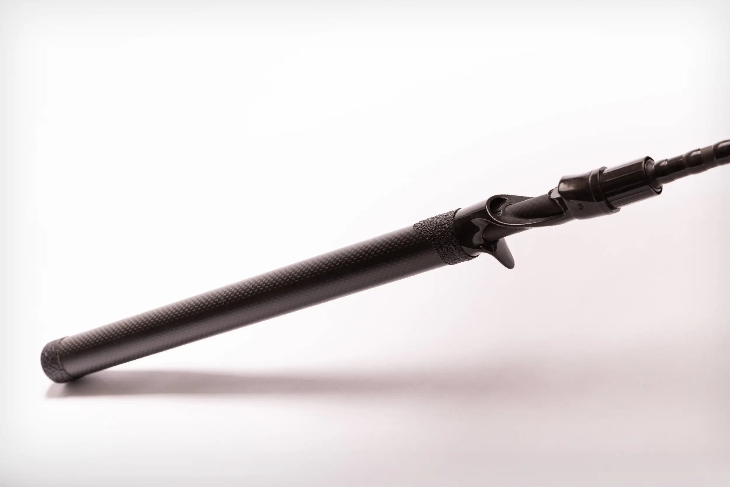 Close-up of a sleek black fishing rod handle with a textured grip on a plain white background.