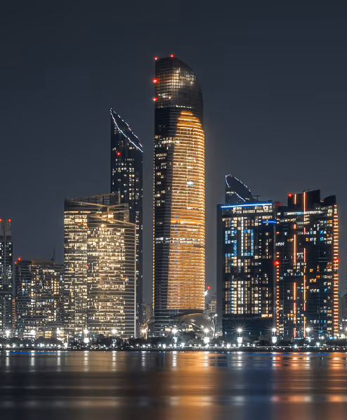 Abu Dhabi skyline at night with illuminated skyscrapers reflecting on the water
