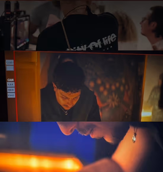 Film crew member working with equipment under dramatic orange lighting on a movie set