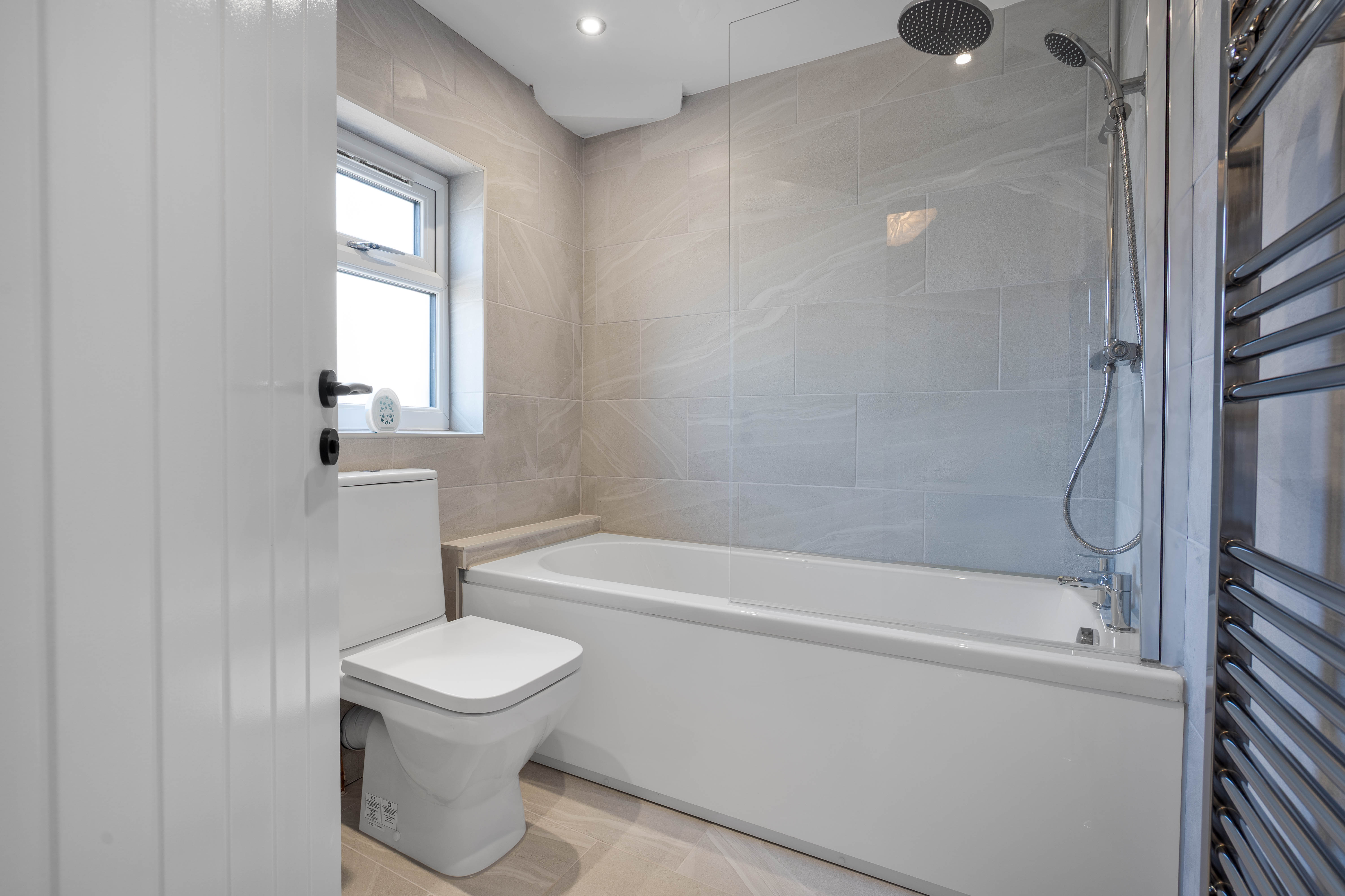 Modern bathroom installation with bath and tiled walls completed in Manchester