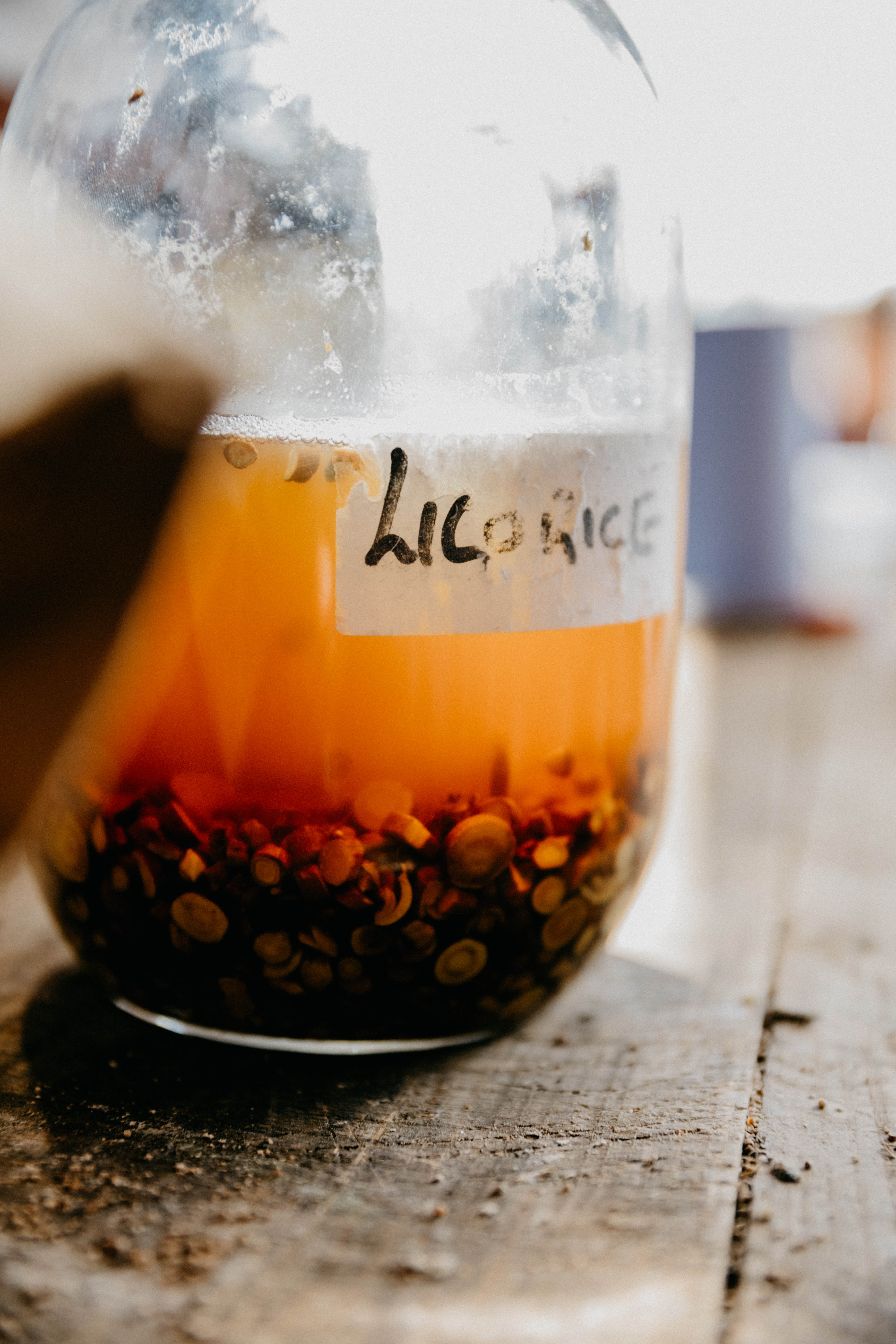 Glass jar labeled Licorice with liquid and small brown pieces soaking at the bottom.