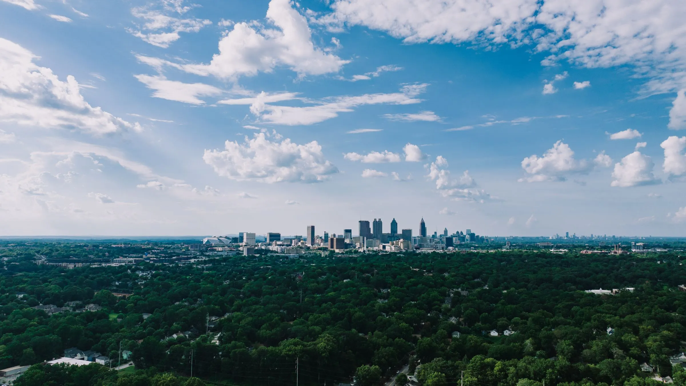 Aerial view of the Atlanta skyline above green tree canopy