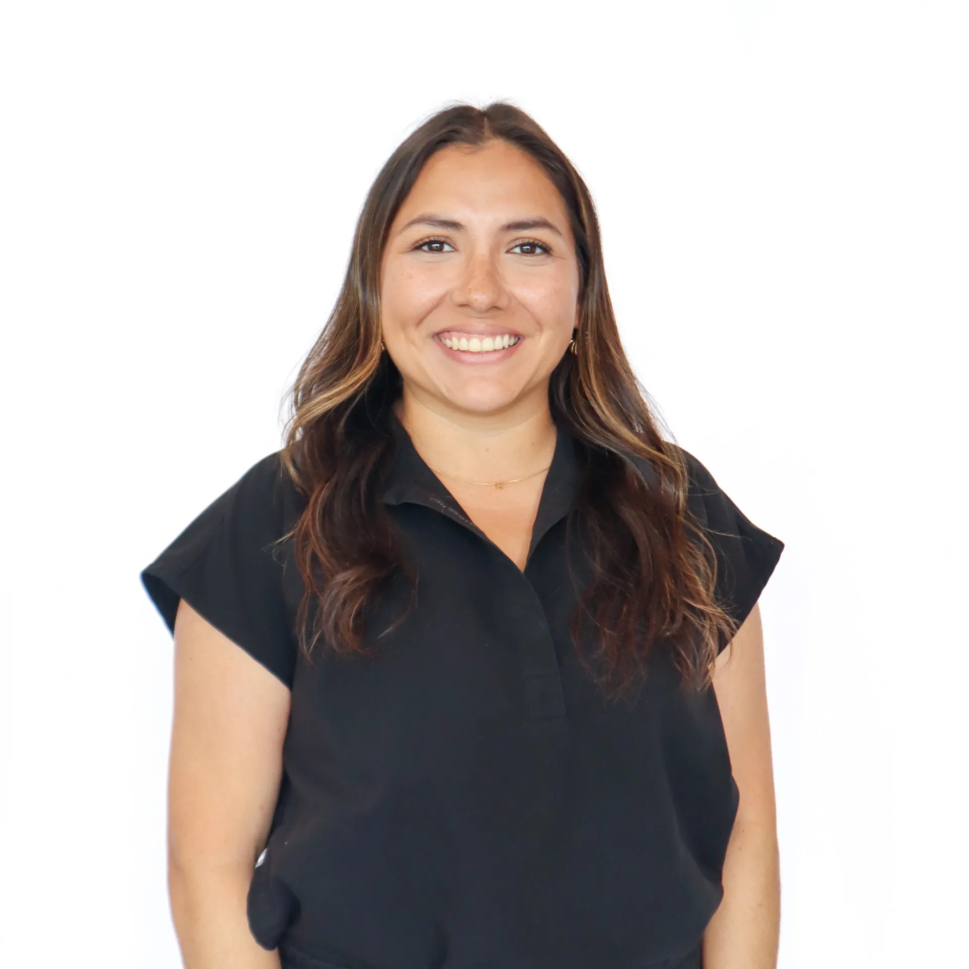 Smiling woman with long brown hair wearing a black short-sleeve blouse against a white background.