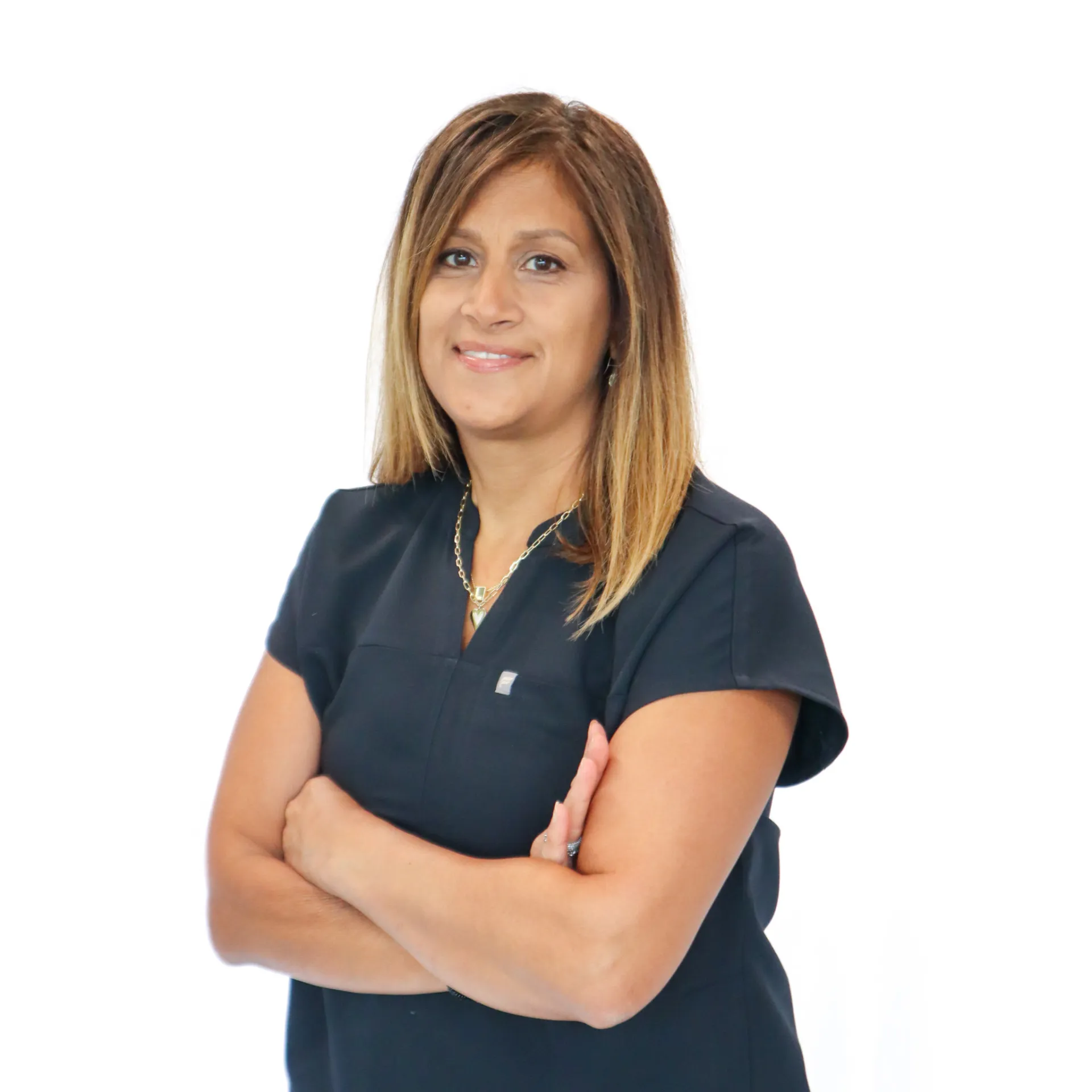 Smiling woman with shoulder-length hair in a black short-sleeve top standing with arms crossed against a white background.