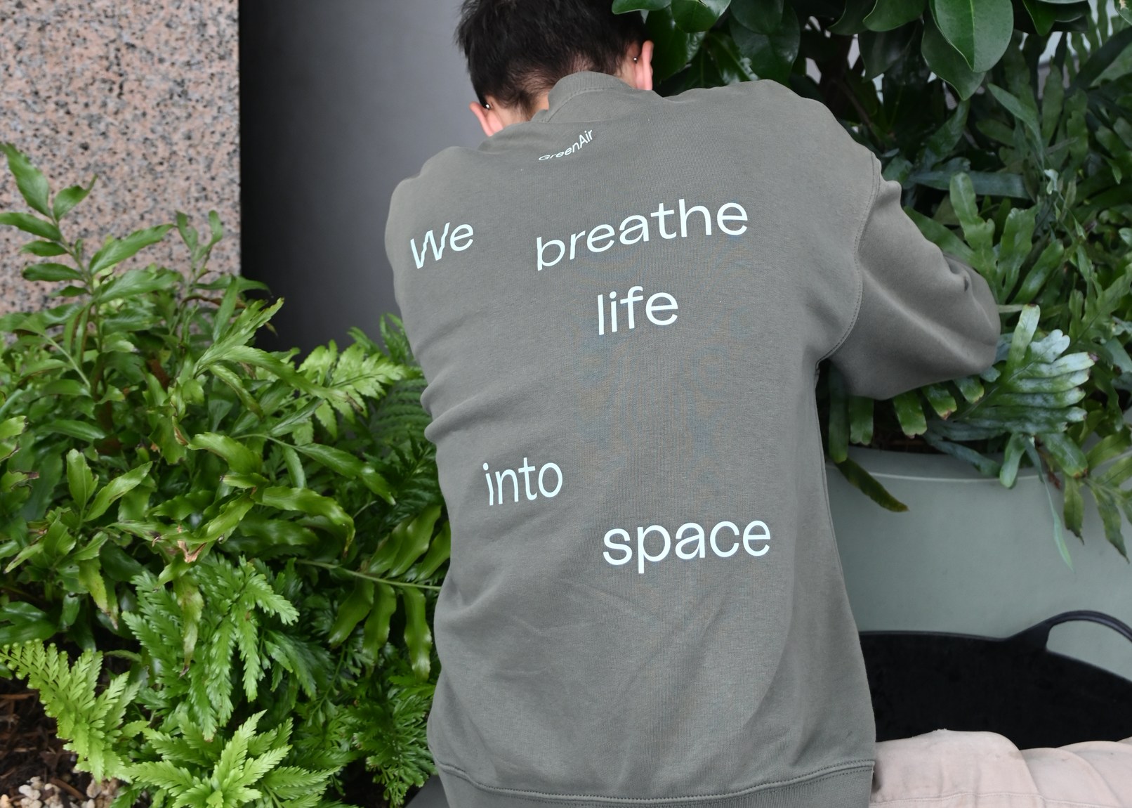 GreenAir technician servicing interior planting on site, shirt reading We breathe life into space