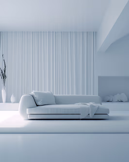 Minimalist white living room with a modern white sofa, cushions, and a throw blanket, set against a backdrop of white vertical curtains and white decor vases.