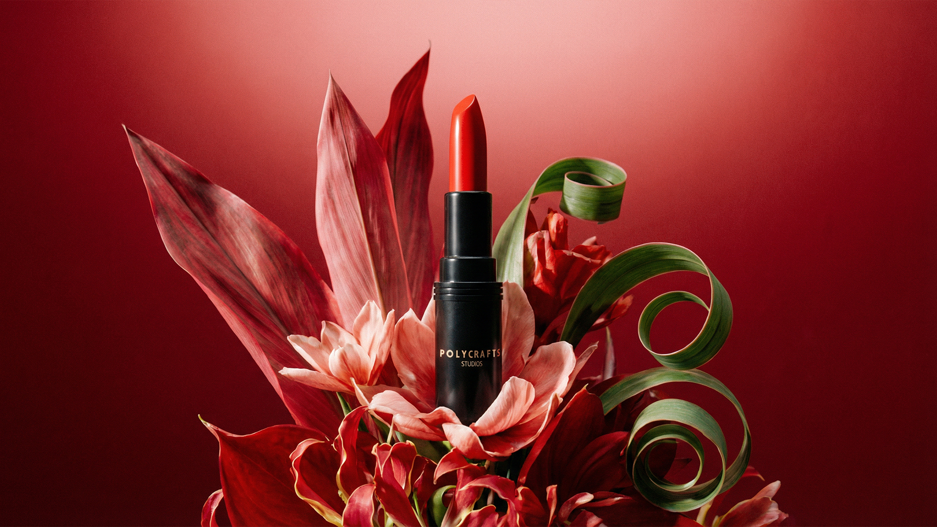 Red lipstick in a black tube surrounded by red and green decorative flowers and leaves against a red background.