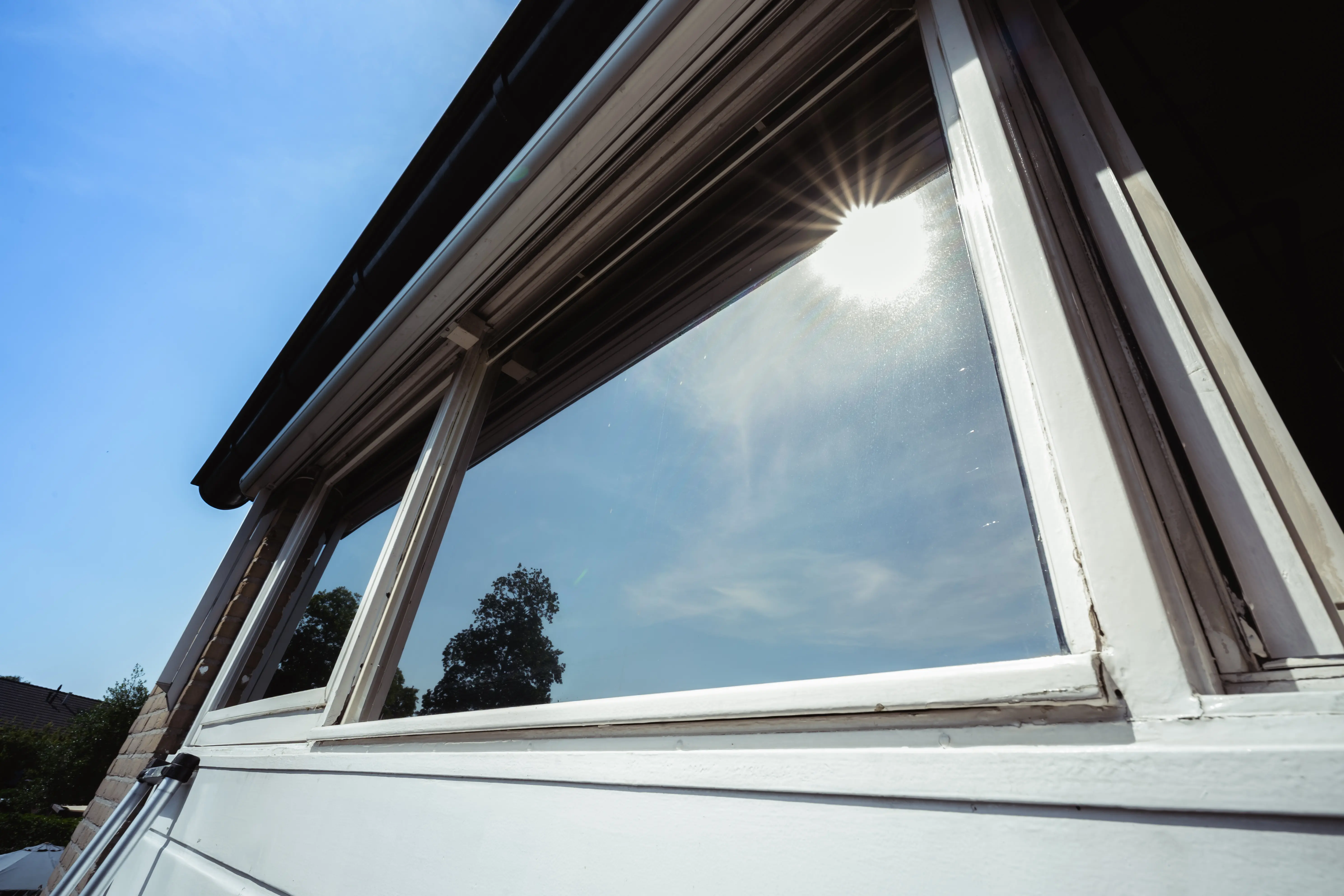 Gevelbeglazing van een woning voorzien van zonwerende raamfolie, met de zon erop