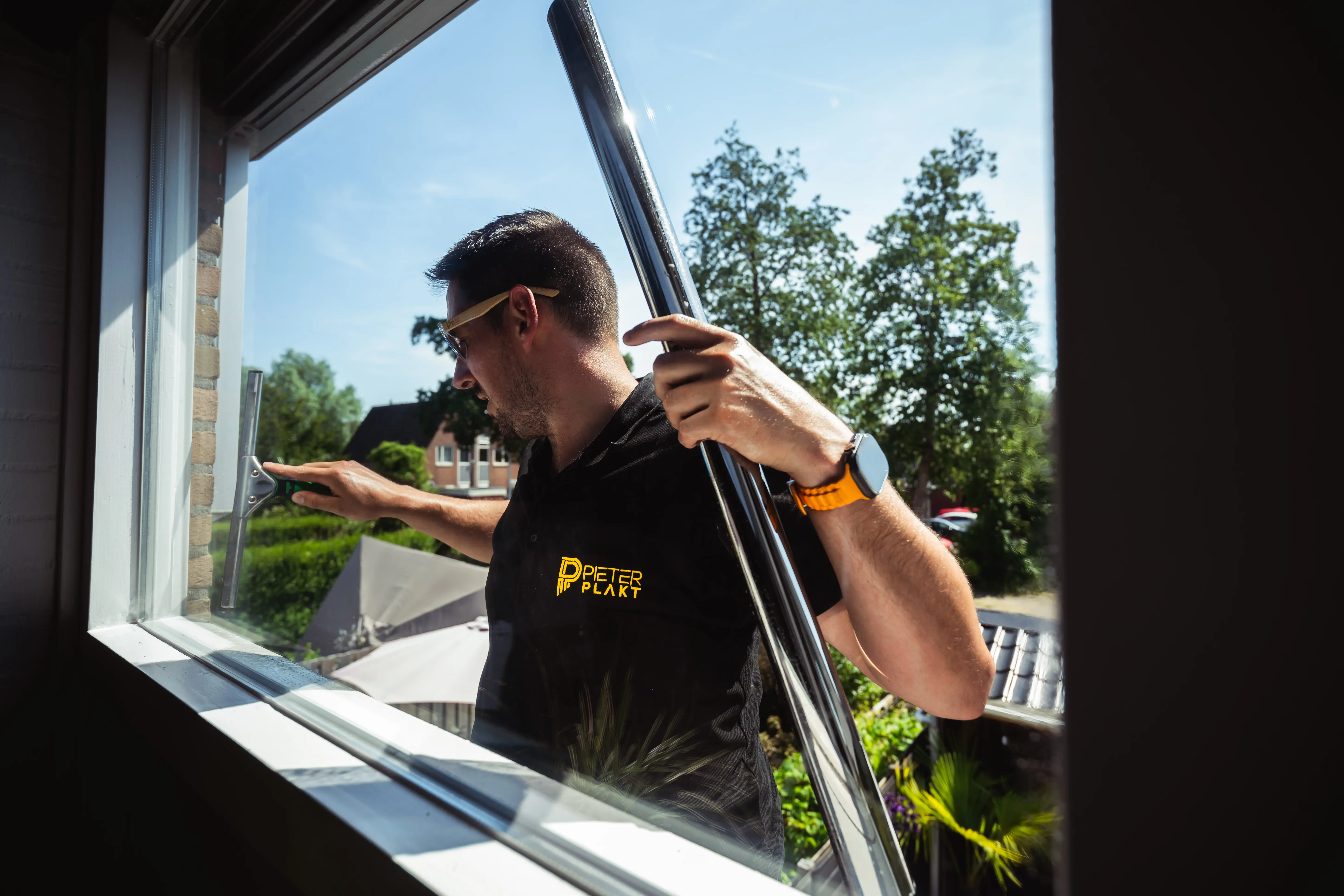 Pieter Plakt brengt zonwerende raamfolie aan op de beglazing van een woning