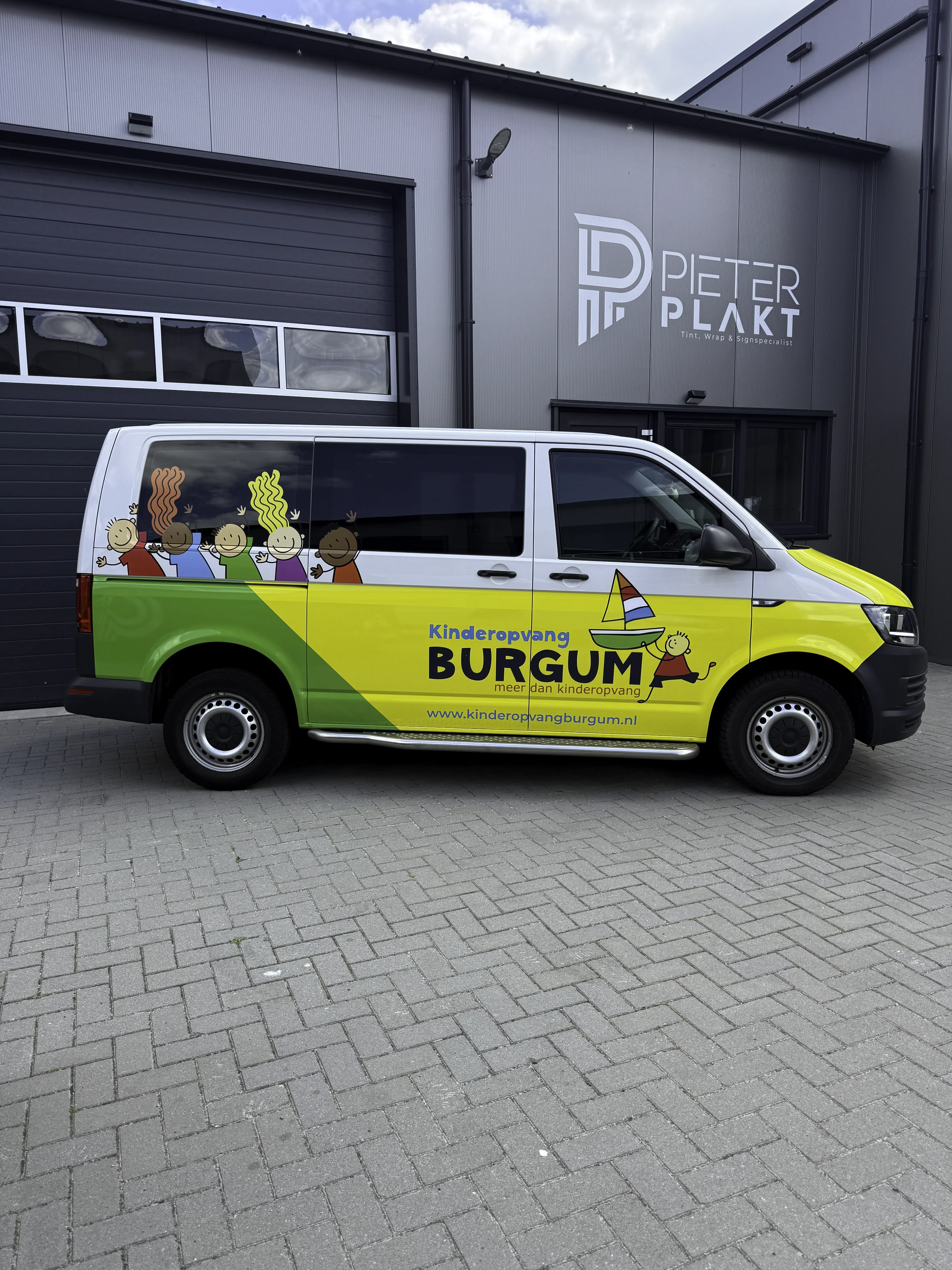 Zijaanzicht van de beletterde Volkswagen Transporter van Kinderopvang Burgum, uitgevoerd door Pieter Plakt