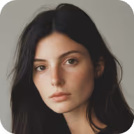 Portrait of a woman with long dark hair and a neutral expression against a plain gray background.