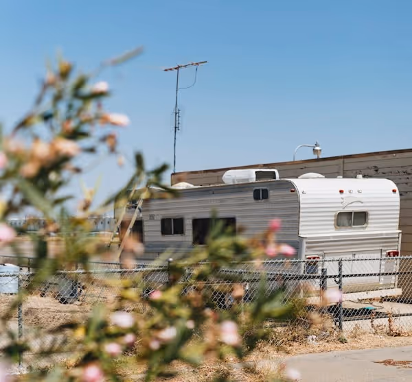 white and brown rv trailer on brown field under blue sky during daytime