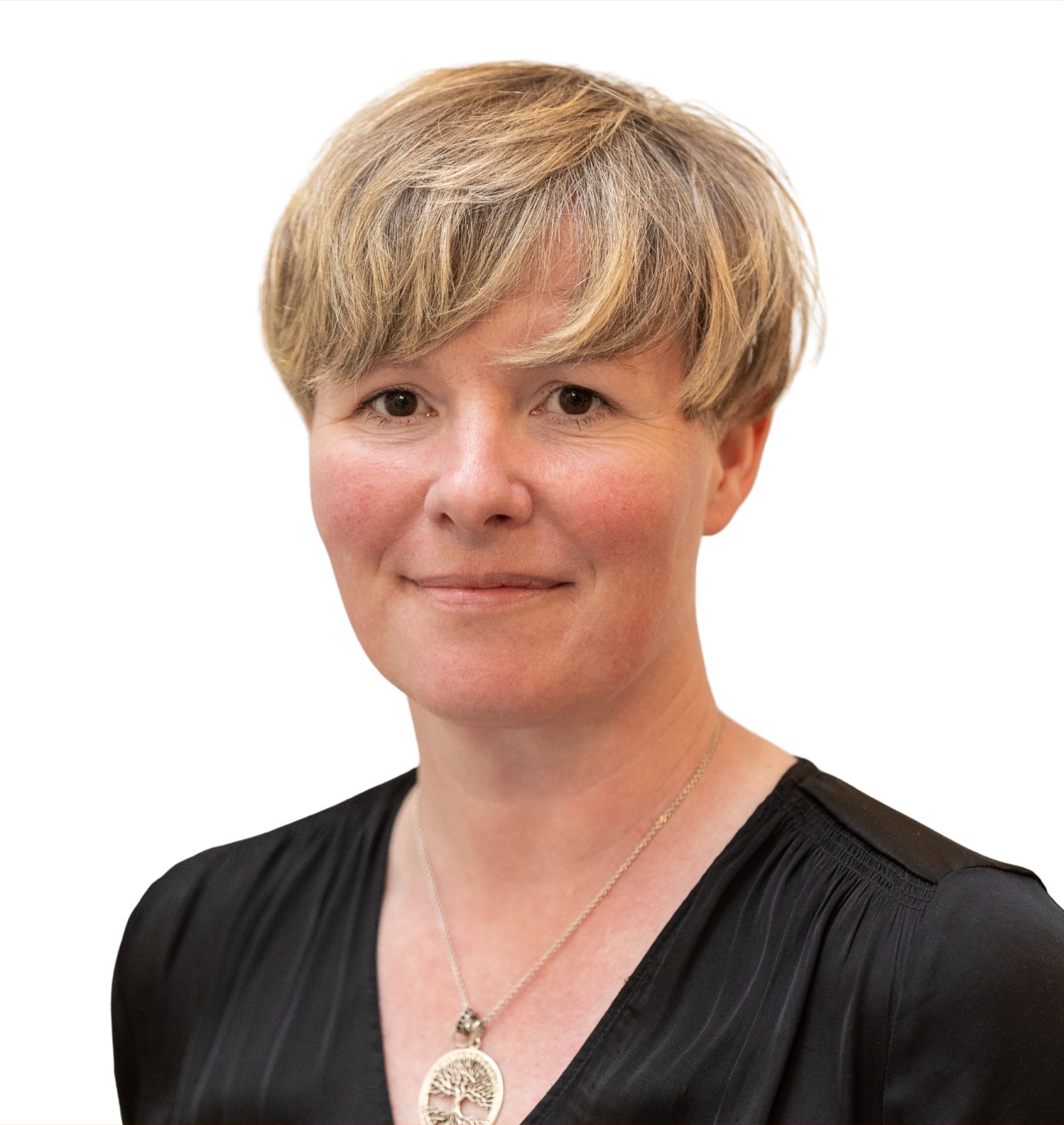 Woman with short blond hair wearing a black blouse and a round pendant necklace with a tree design.