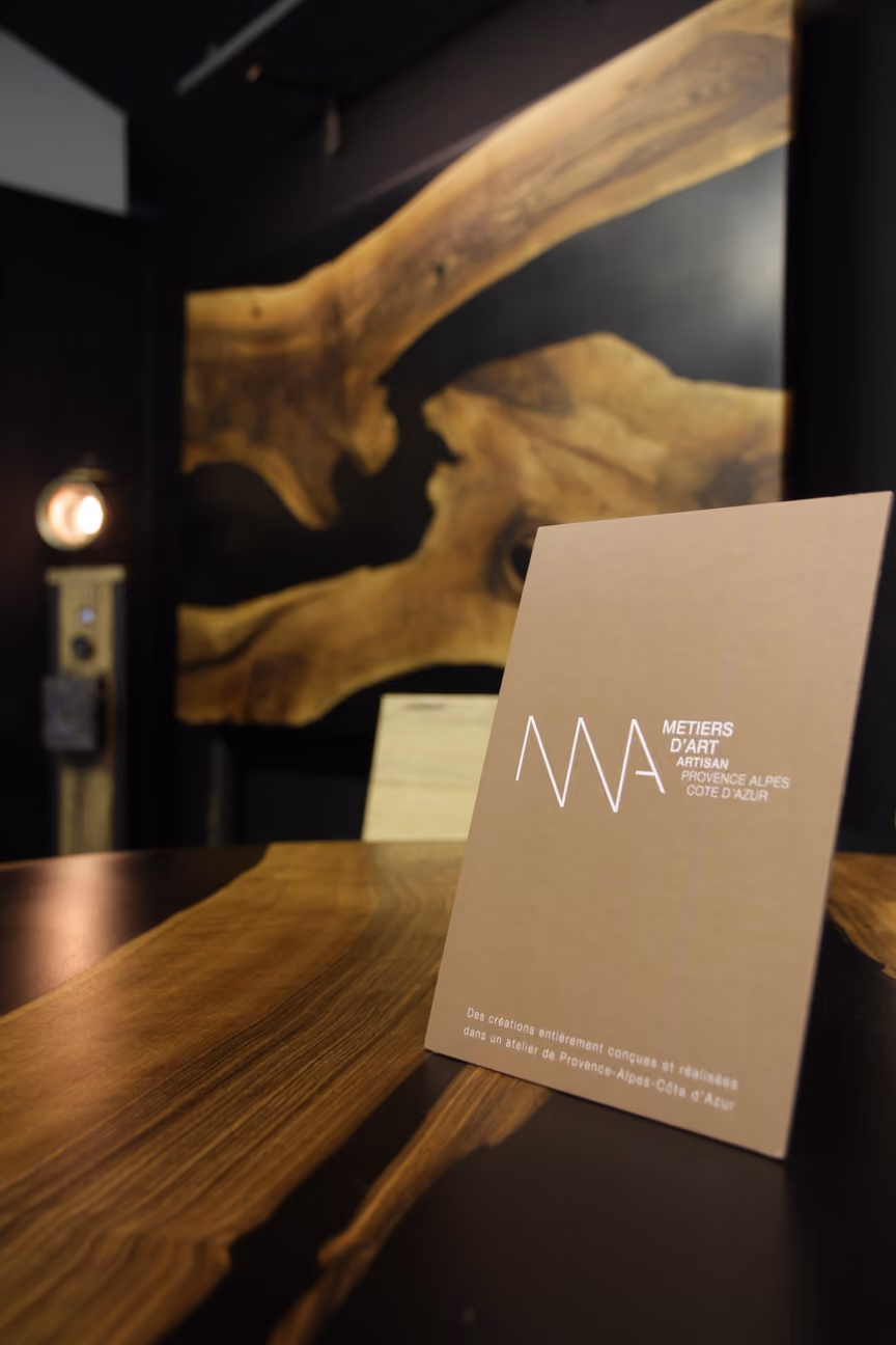Carte de visite beige sur table en bois naturel avec fond de mur noir et décoration en bois.