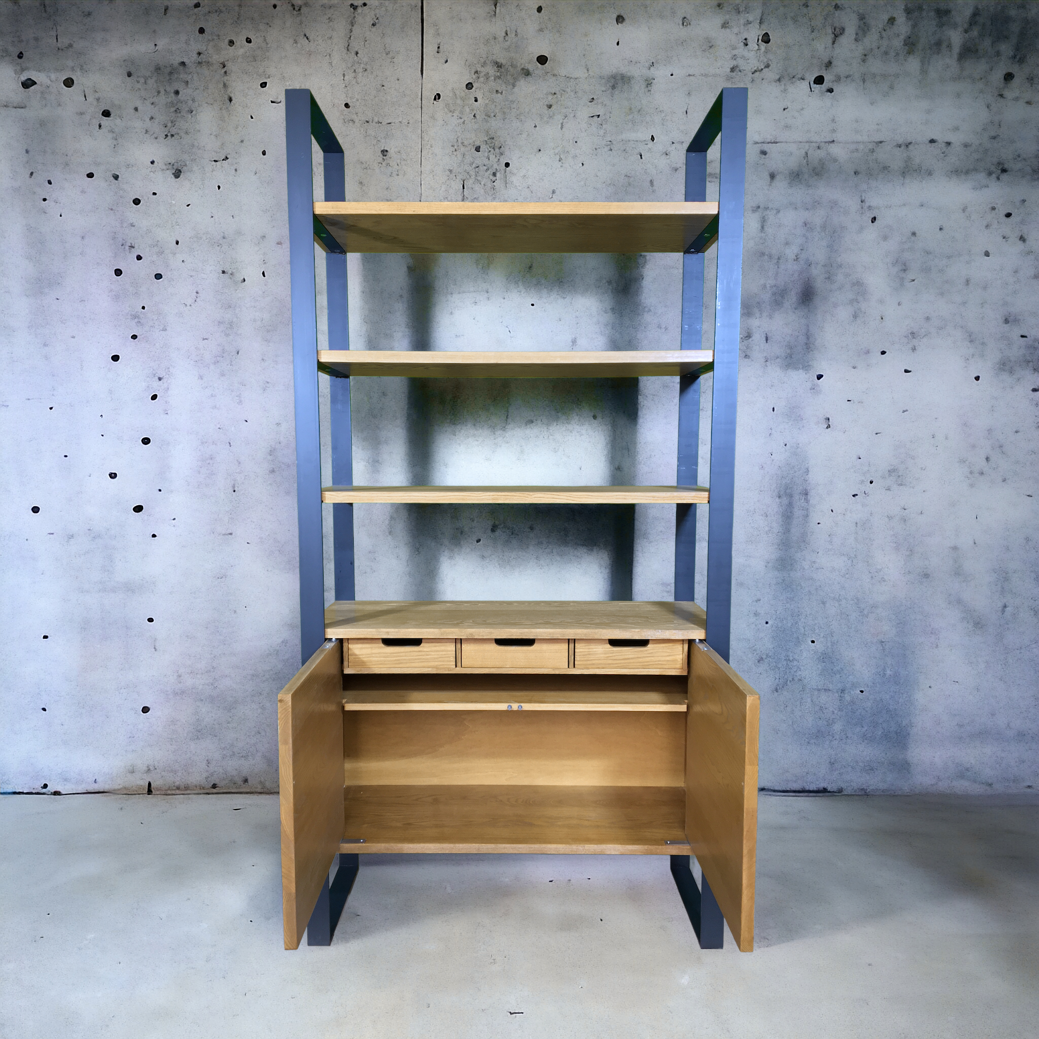 Bibliothèque en bois avec cadre métallique gris, quatre étagères supérieures, trois petits tiroirs et deux portes ouvertes en bas.