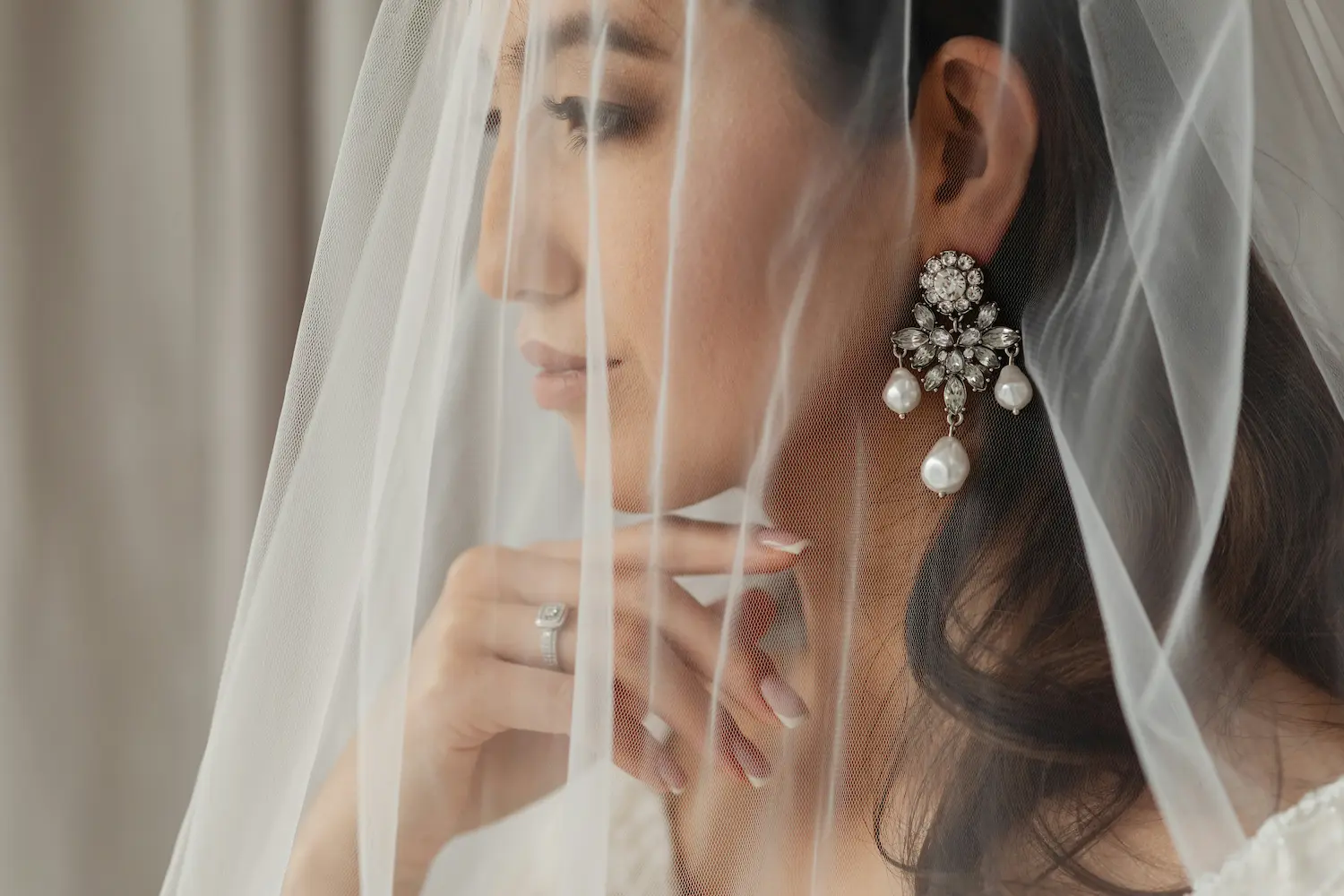 Une mariée pensante dans son costume de mariage, ornée d'oreilles époustouflantes et d'un anneau de mariage brillant.