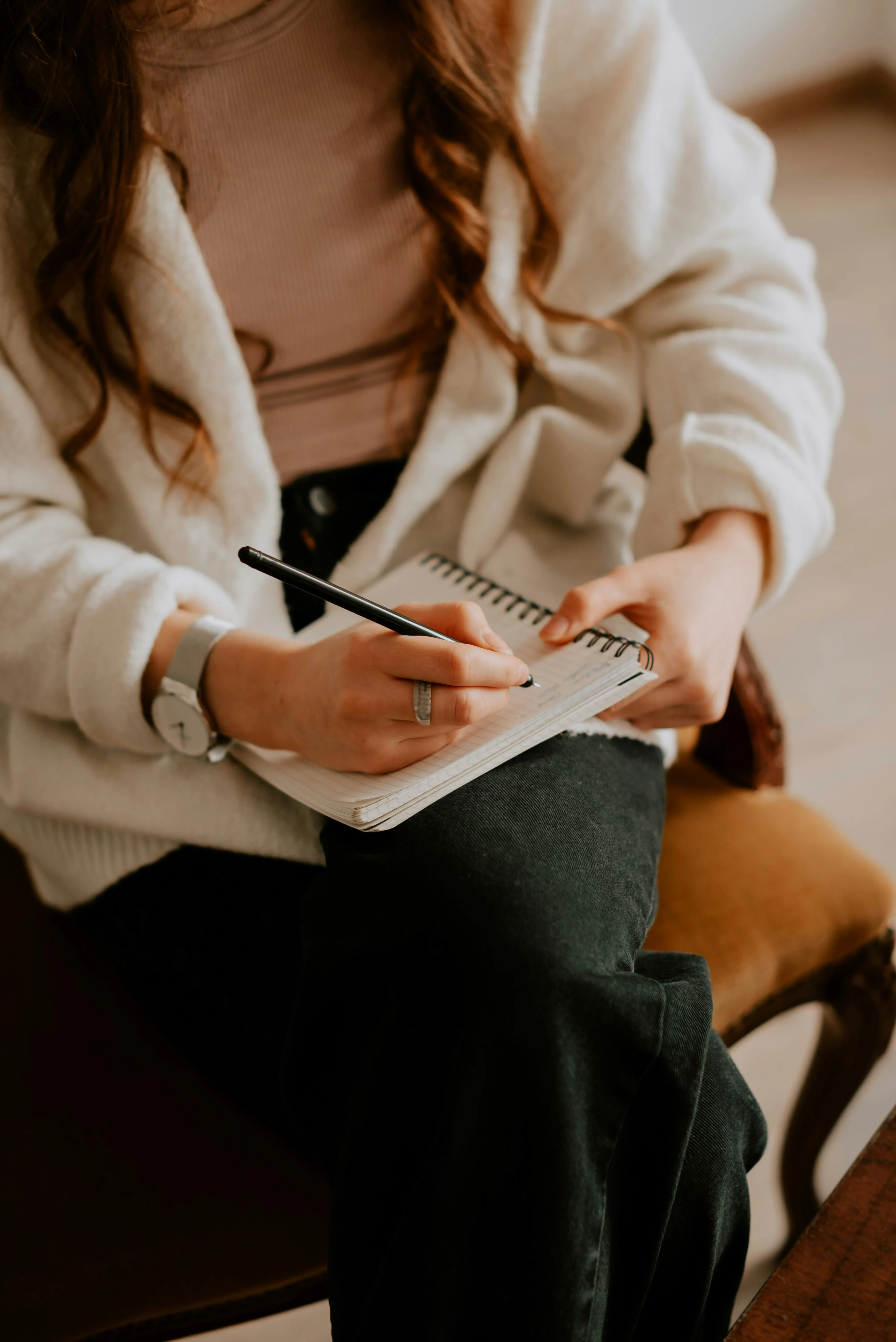 Une jeune femme dans un environnement chaleureux note dans un journal, évoquant un sentiment de réflexion et de tranquillité.