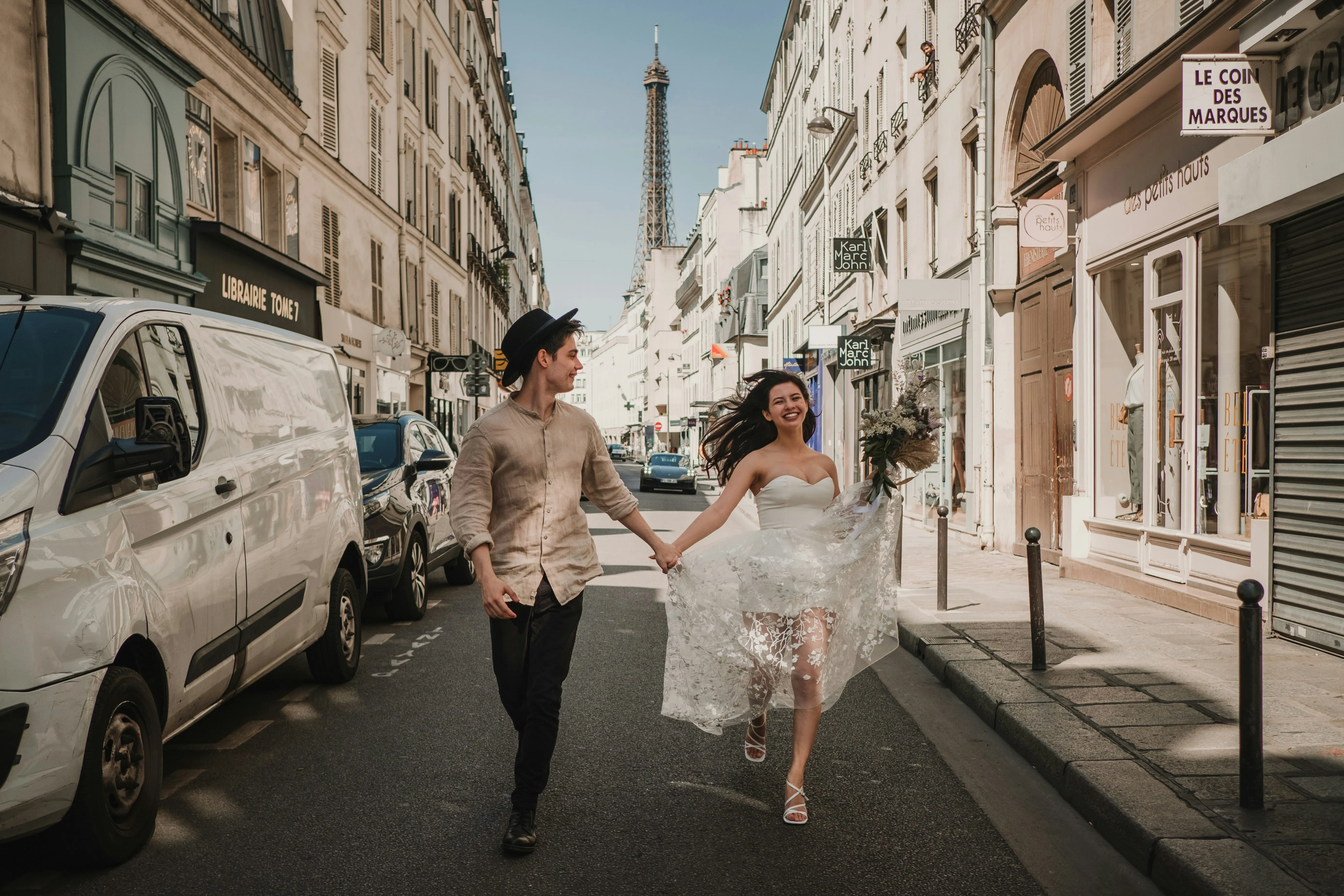 Une jeune mariée dans un robe époustouflante de dentelle et une jeune homme dans un chemisier crêpe marchent main dans