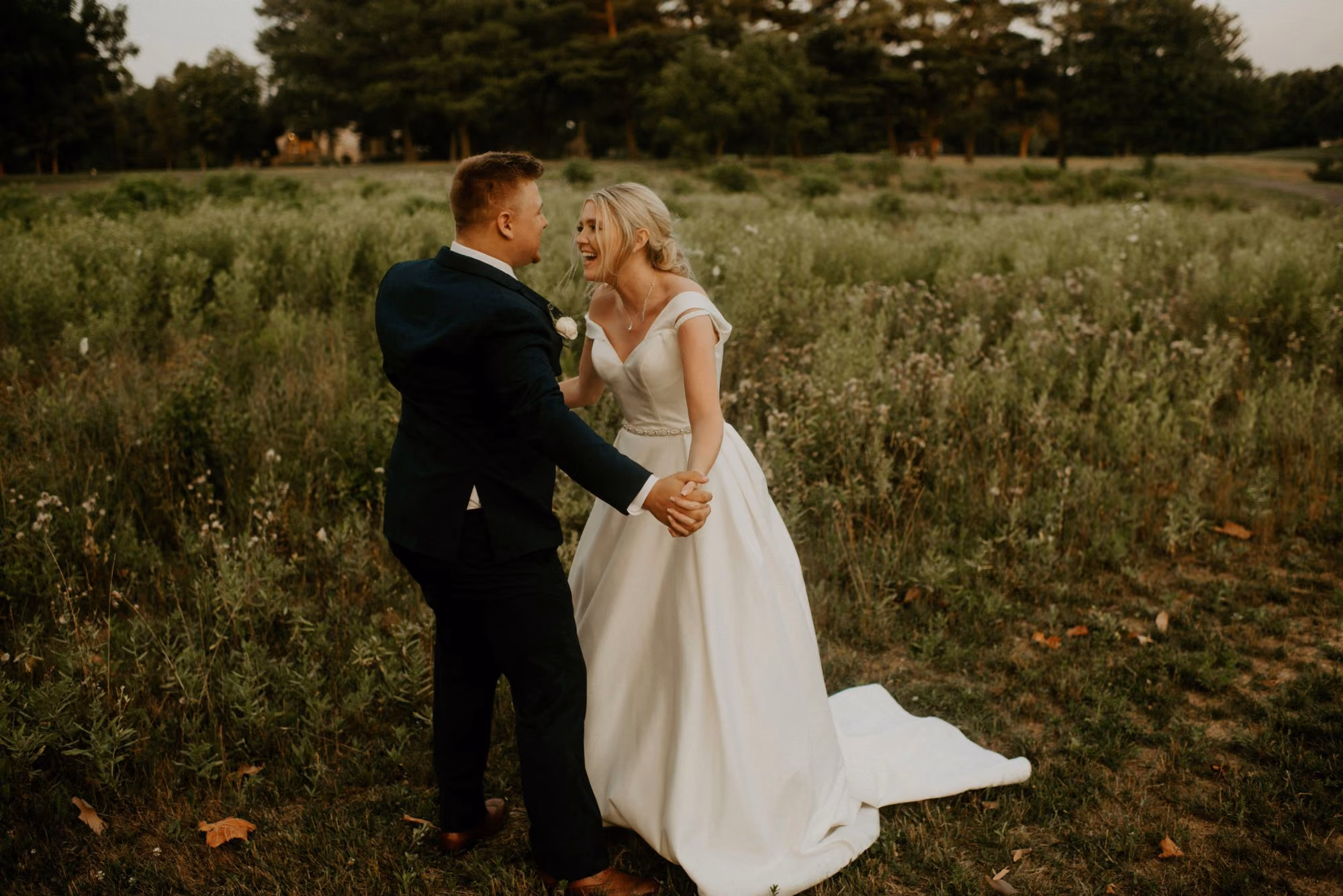 Un couple de mariée et de marié partageant un moment tendre dans un champ verdoyant, capturant l'essence de la romance