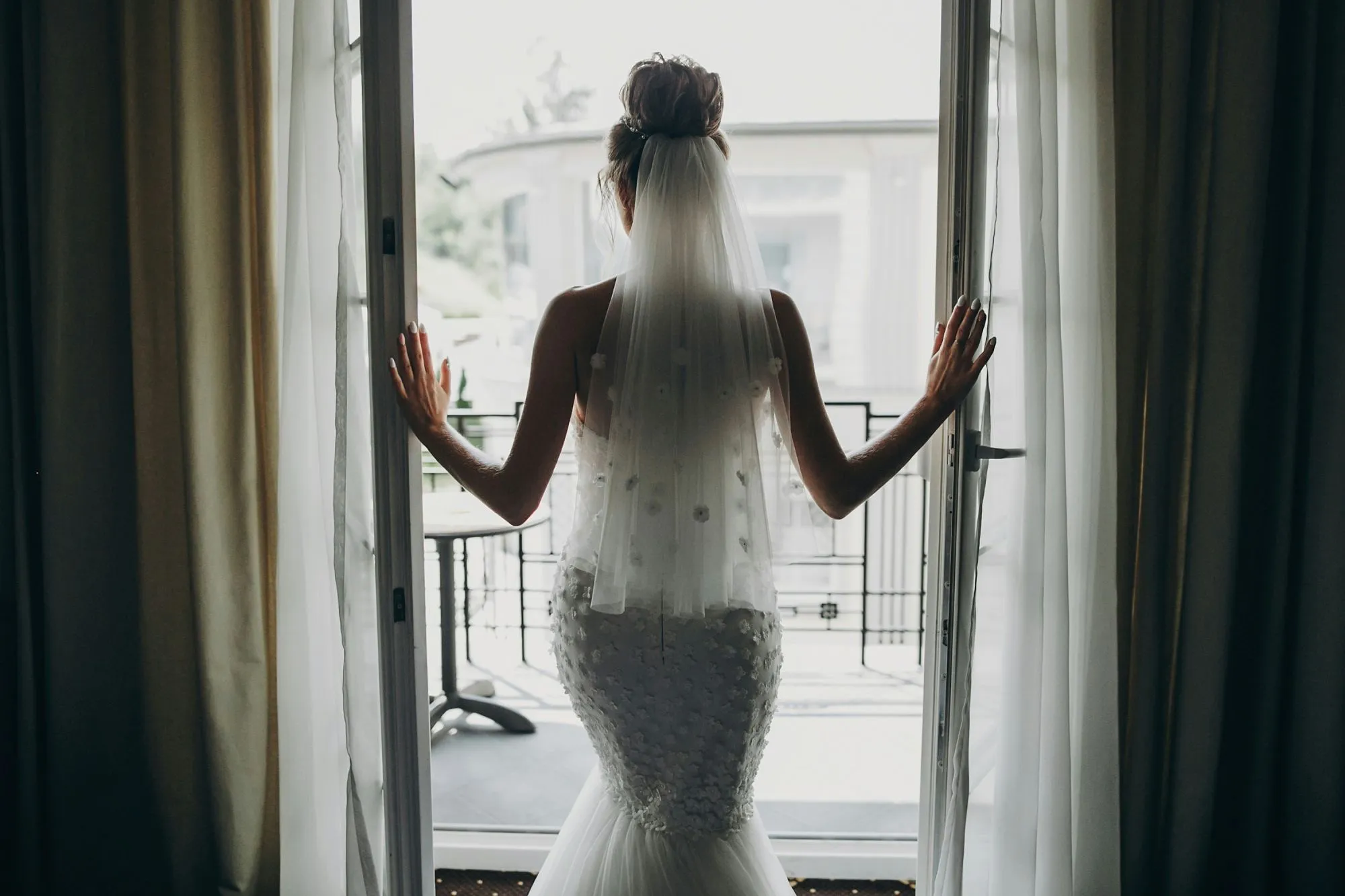 Une mariée en robe blanche et dentelle s'élève dans un décor intérieur, attendant avec excitation le début de son mariage.