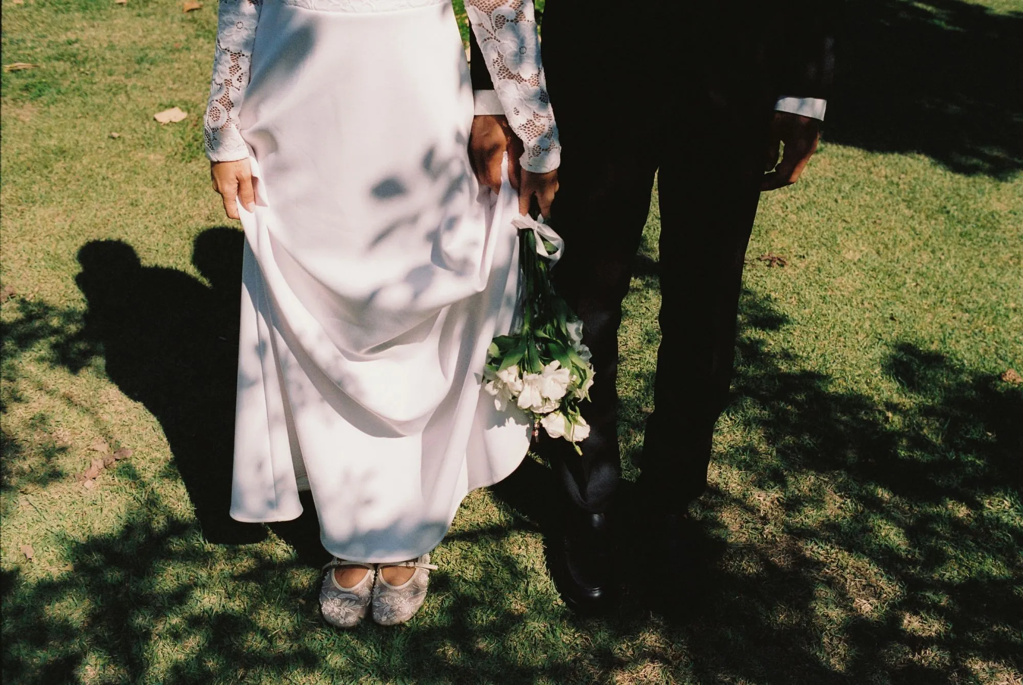 Un couple en amour partage un moment tendre dans un parc luxuriant, le mari tenant un bouquet de fleurs blanches, le