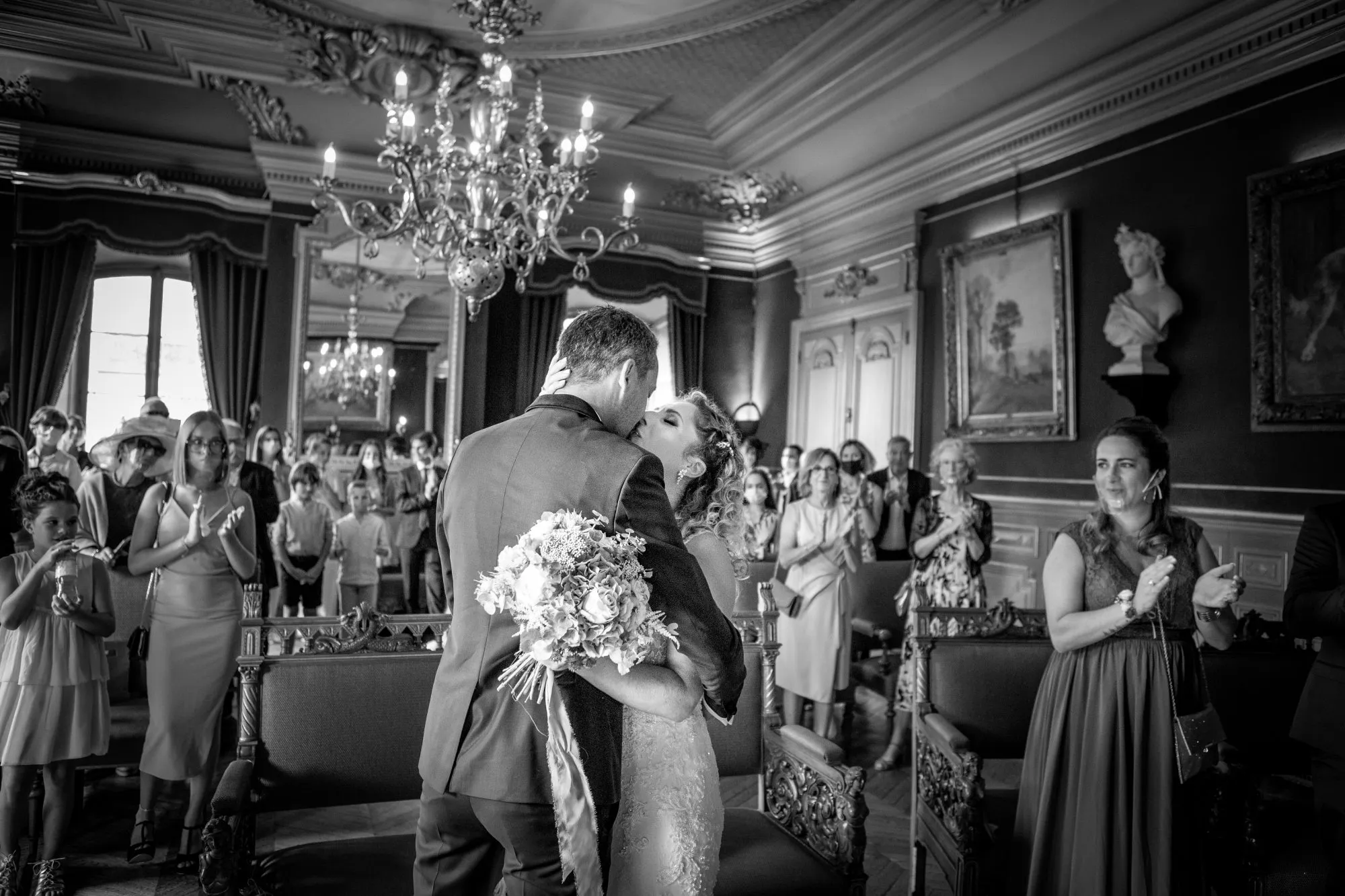 Un couple romantique partage un baiser tendre au sein d'un décor élégant et classique, célébrant leur mariage dans un